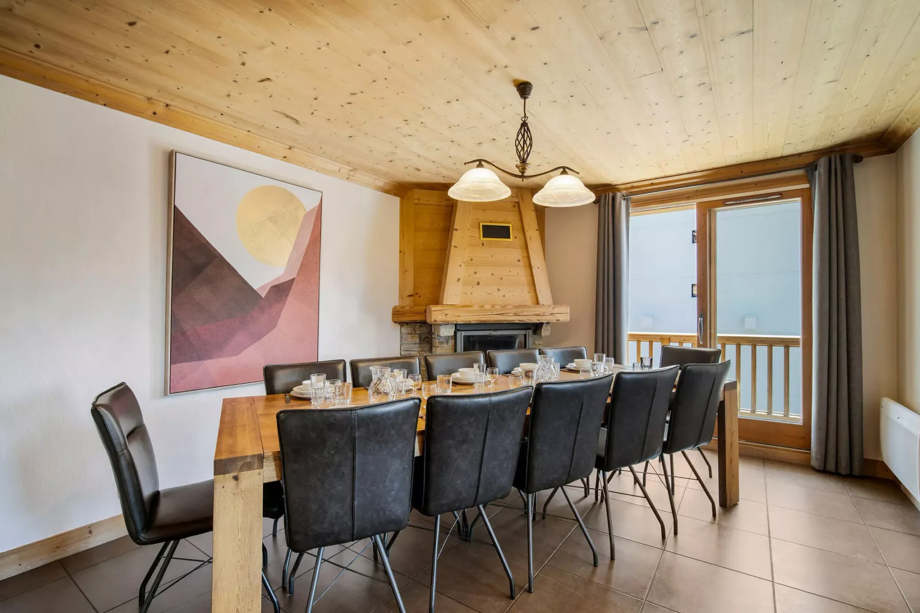 Un comedor con una mesa larga y asientos oscuros junto a grandes ventanas.