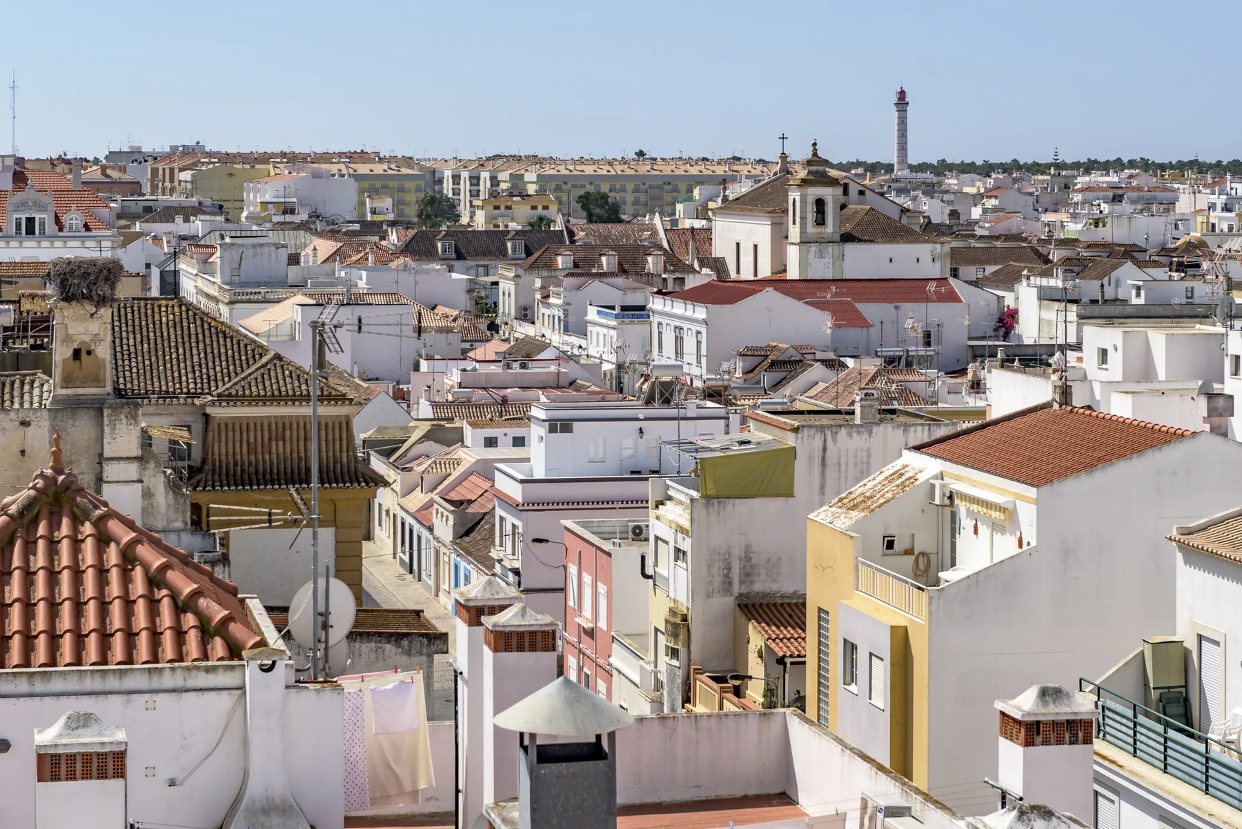 Vista elevada de los tejados de una localidad, con una torre de iglesia al fondo.