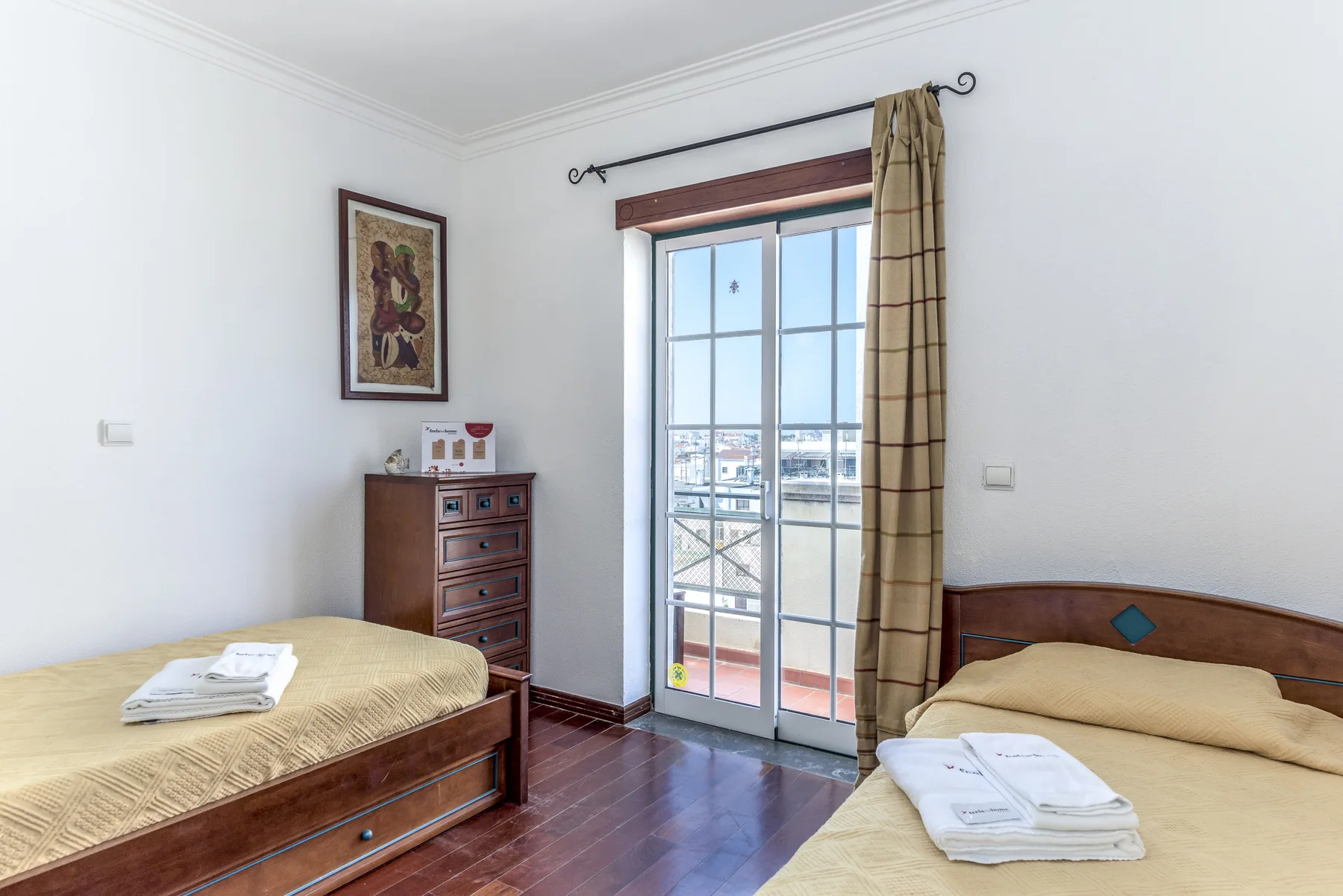 Un dormitorio con dos camas, una cómoda y puertas acristaladas que dan a un balcón.