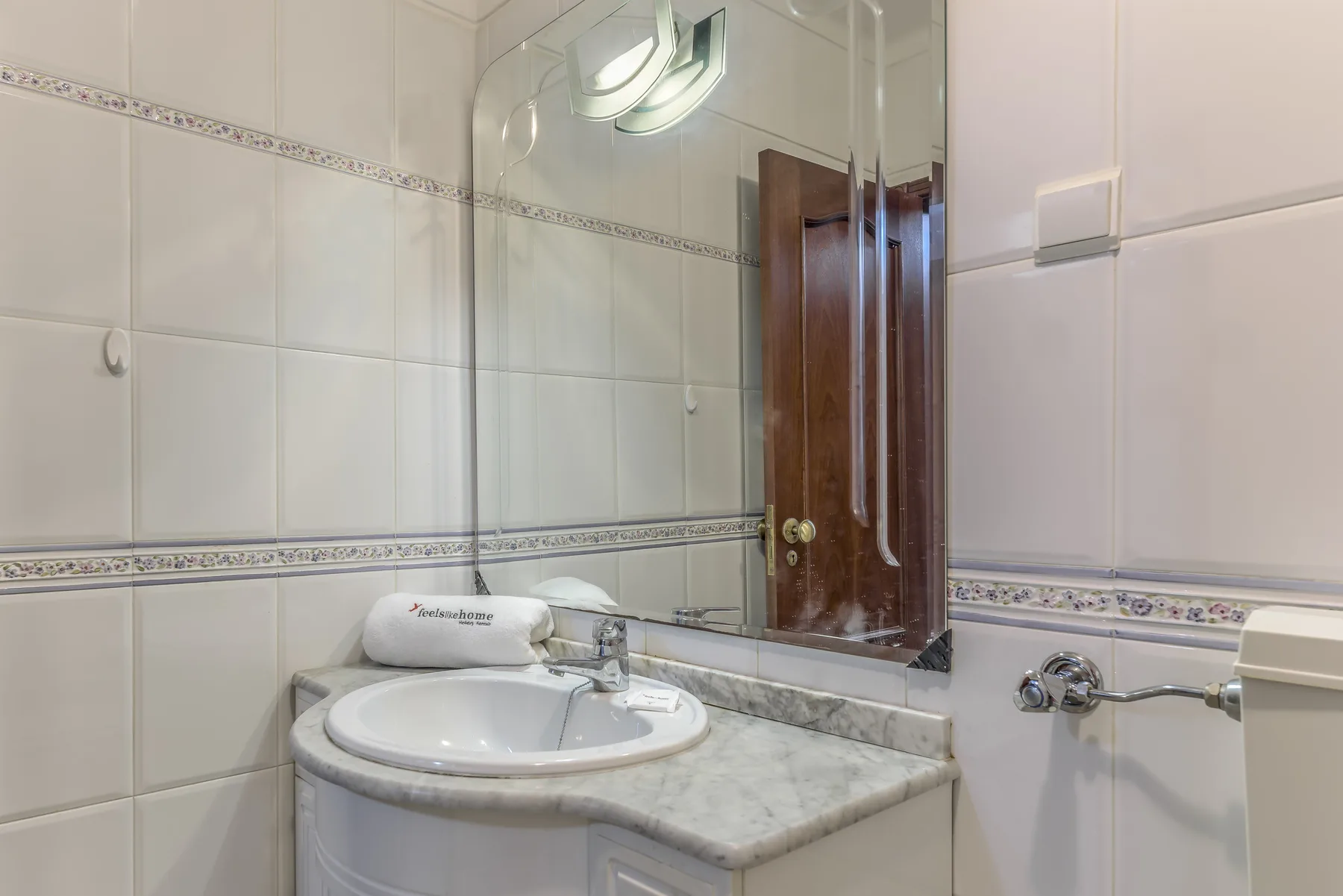 Un baño alicatado cuenta con un lavabo y un espejo grande.