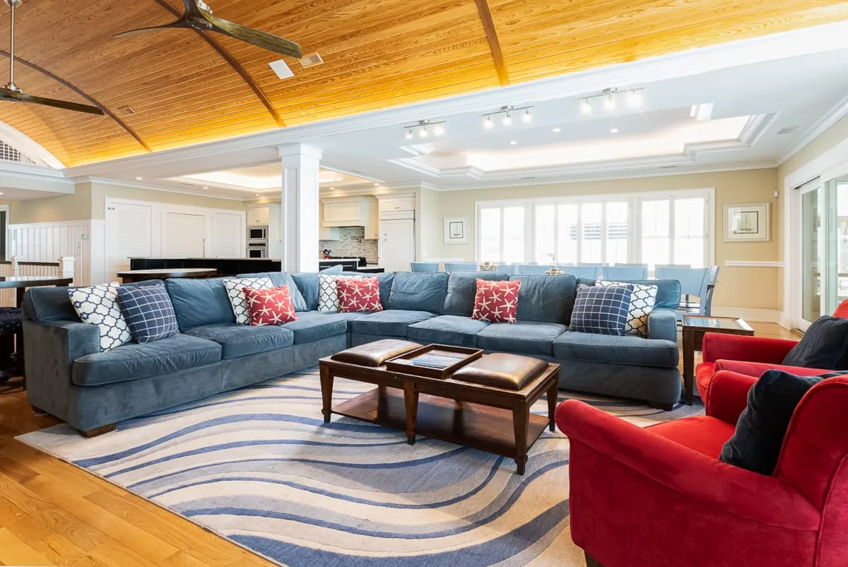 Una sala luminosa con asientos azules, sillones rojos y una mesa de centro de madera.