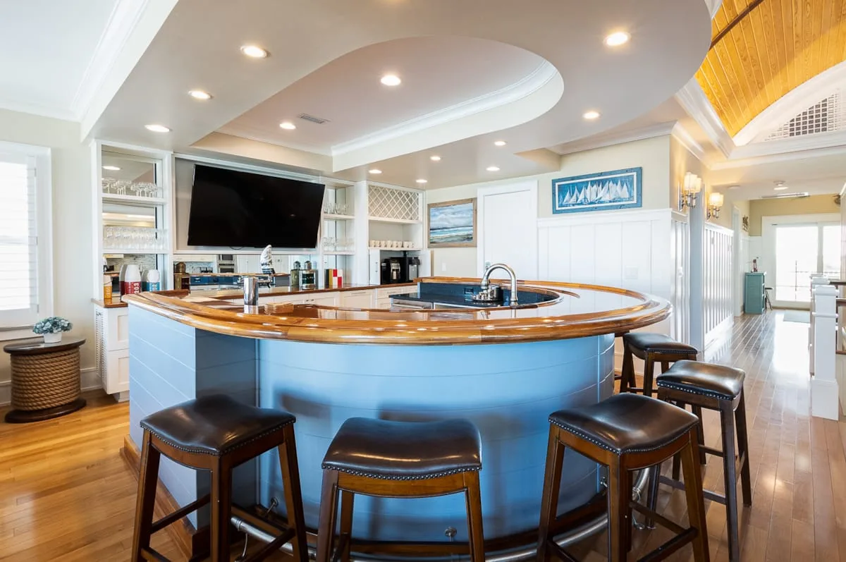Una cocina luminosa cuenta con una isla curva con encimera de madera y asientos de bar.