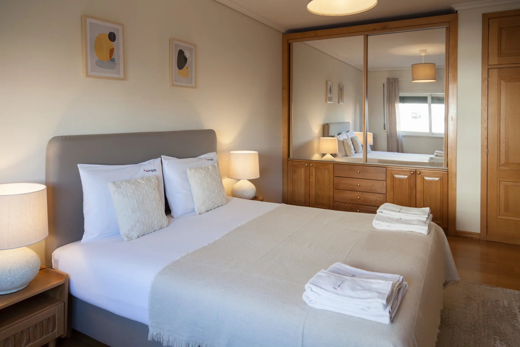 Un dormitorio con una cama bien hecha y un armario de madera.