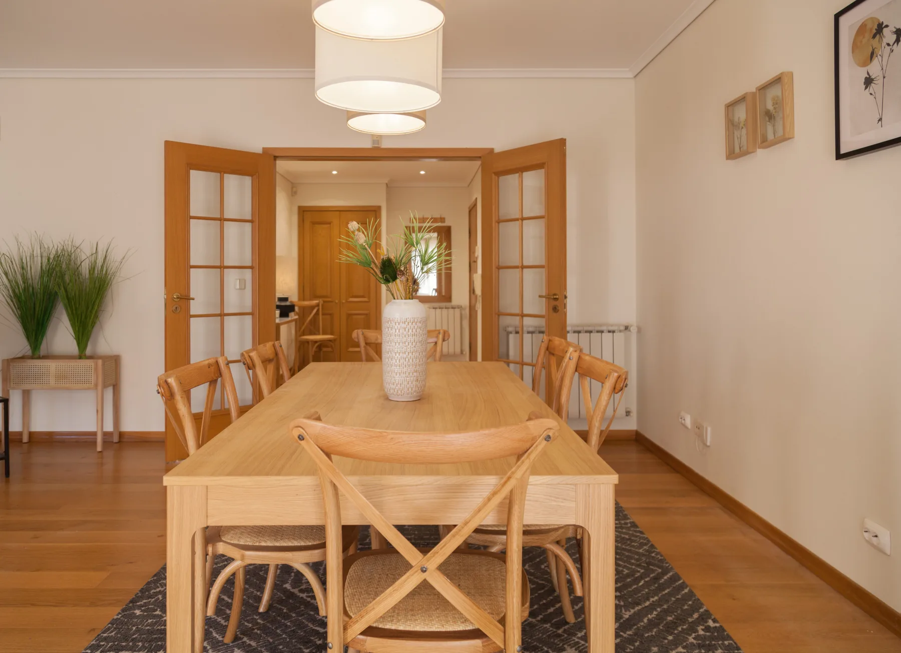 Comedor con una mesa de madera y sillas bajo lámparas colgantes.