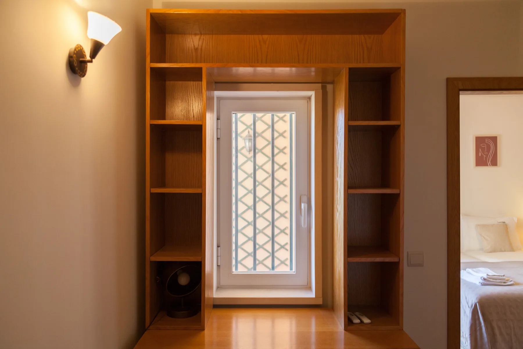 Una puerta de dormitorio está enmarcada por estanterías de madera alrededor de una ventana.