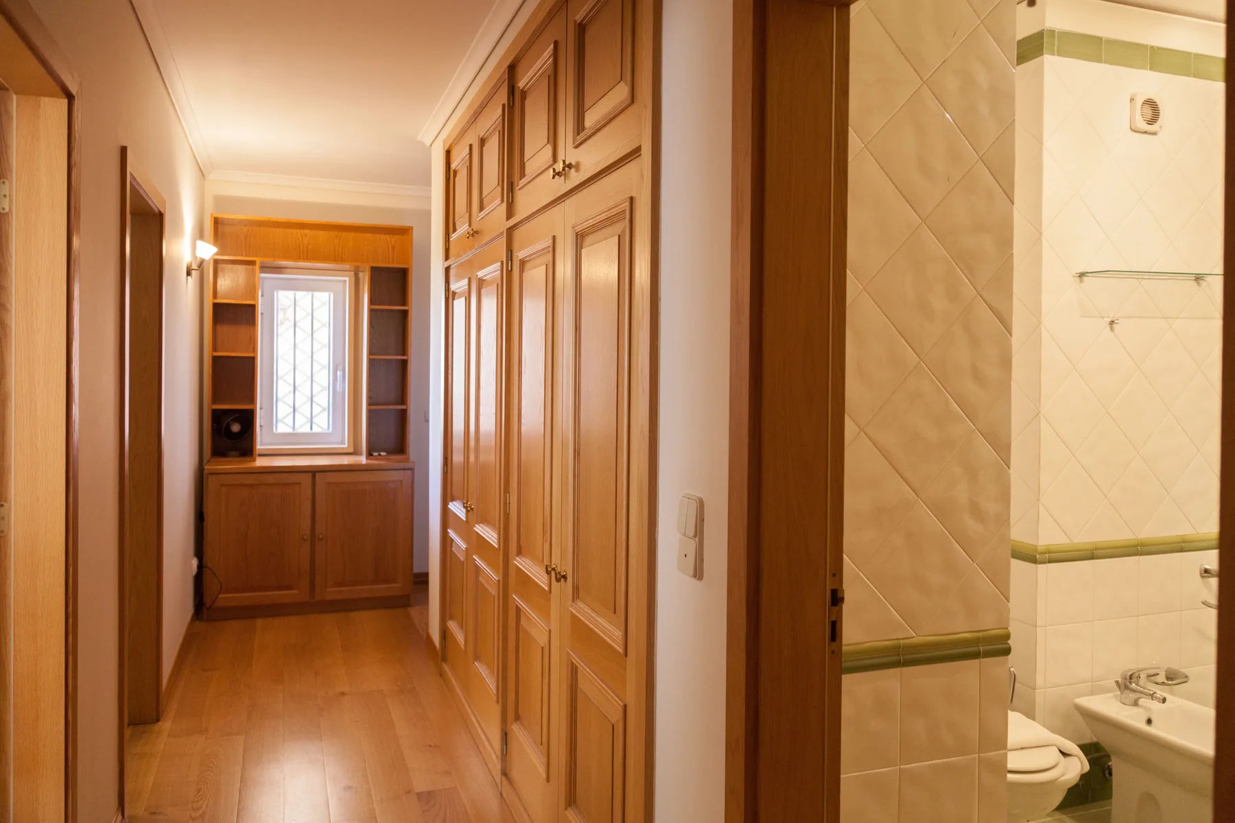 Un pasillo con armarios de madera conduce a un baño.