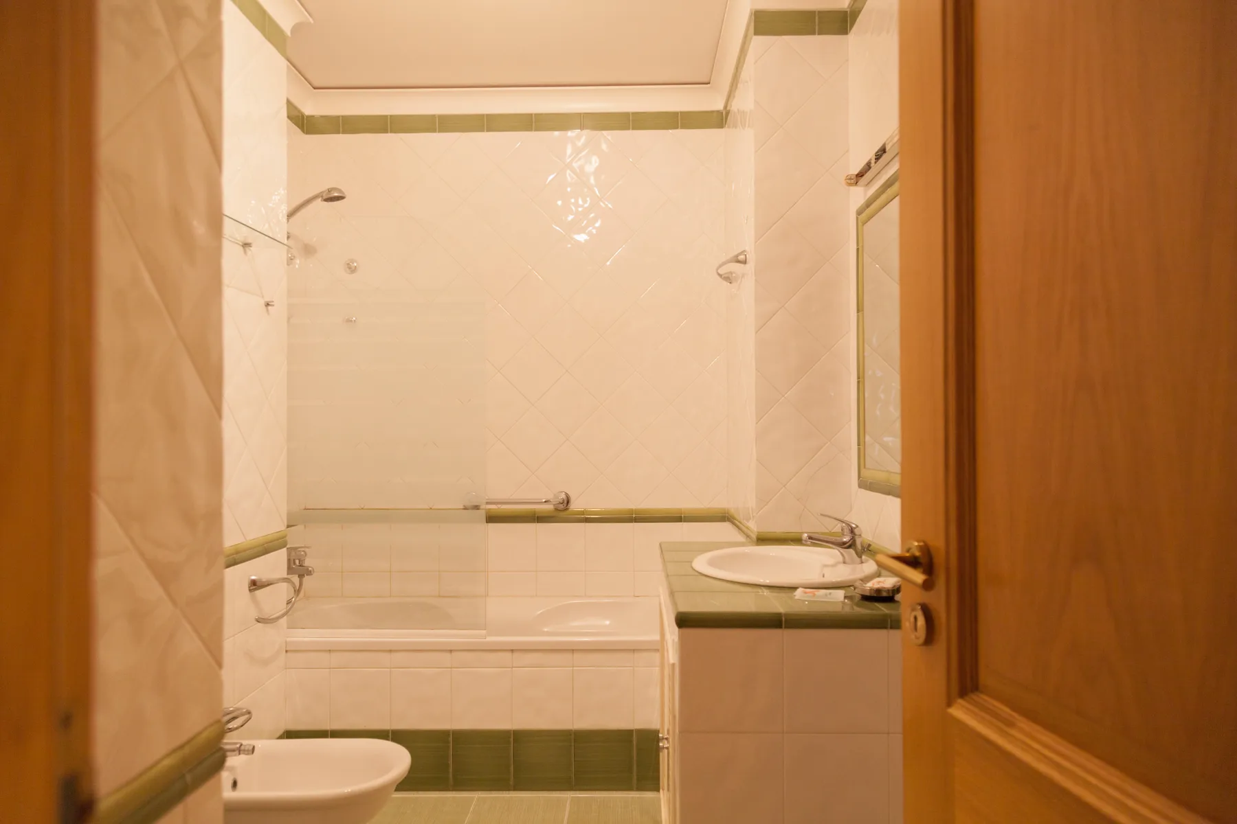 Un baño alicatado con bañera, lavabo y puerta de madera.
