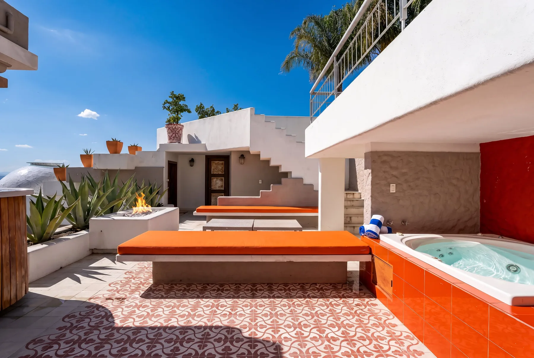A sunny outdoor terrace features a built-in bench and a small hot tub.