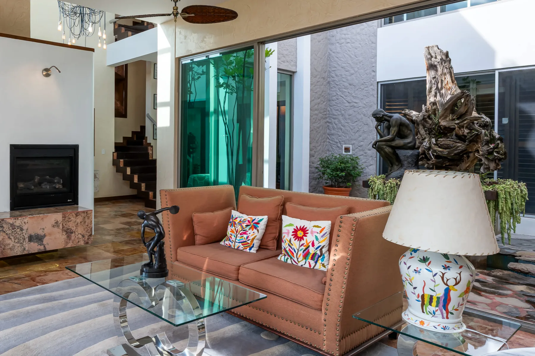 A living room with a sofa and glass coffee table beside large windows.