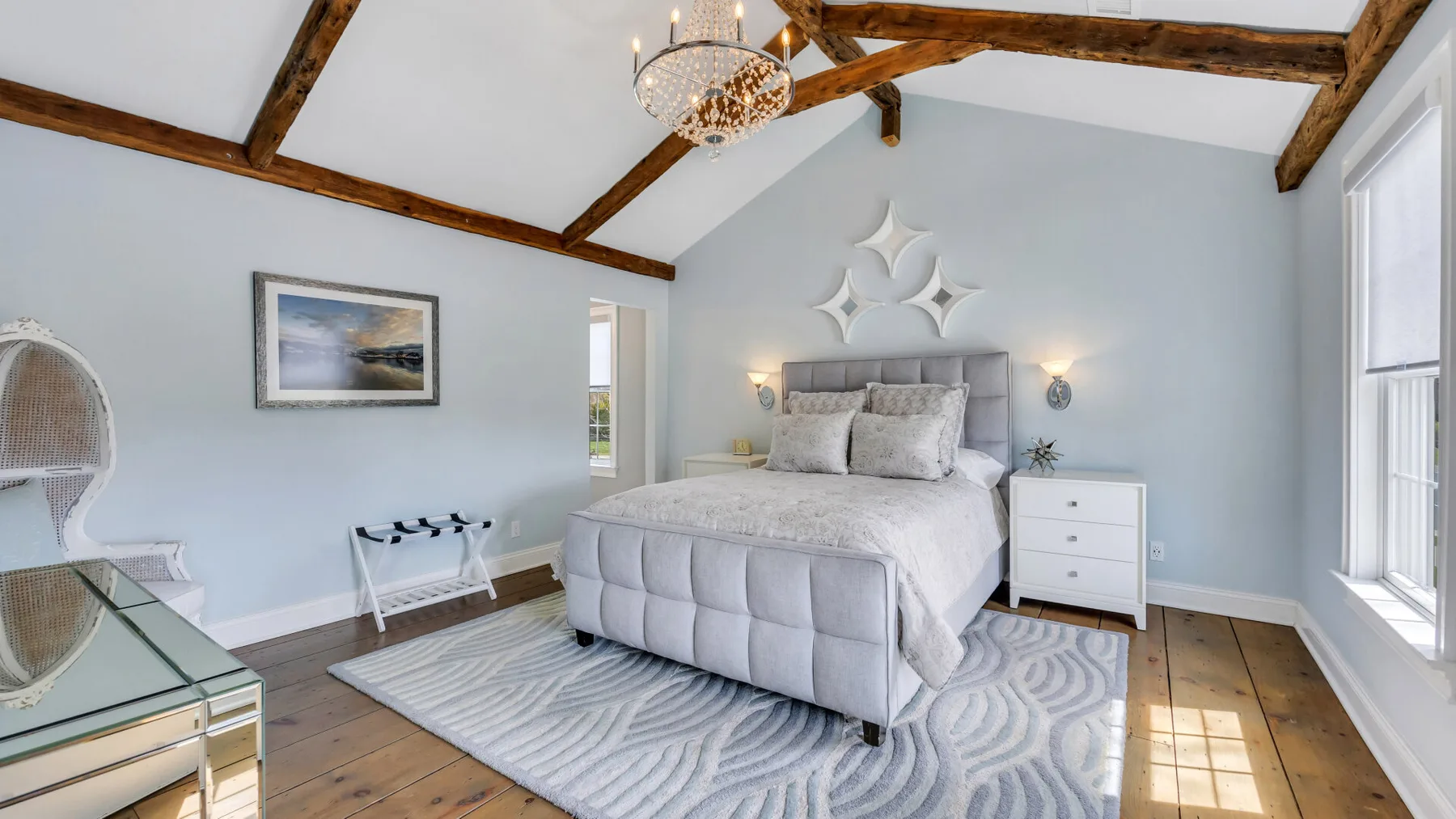 Un dormitorio luminoso con una cama grande bajo vigas expuestas.