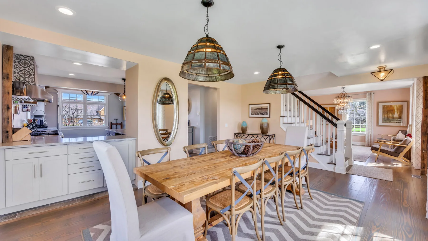 Comedor abierto junto a la cocina, con una mesa de madera y una escalera.
