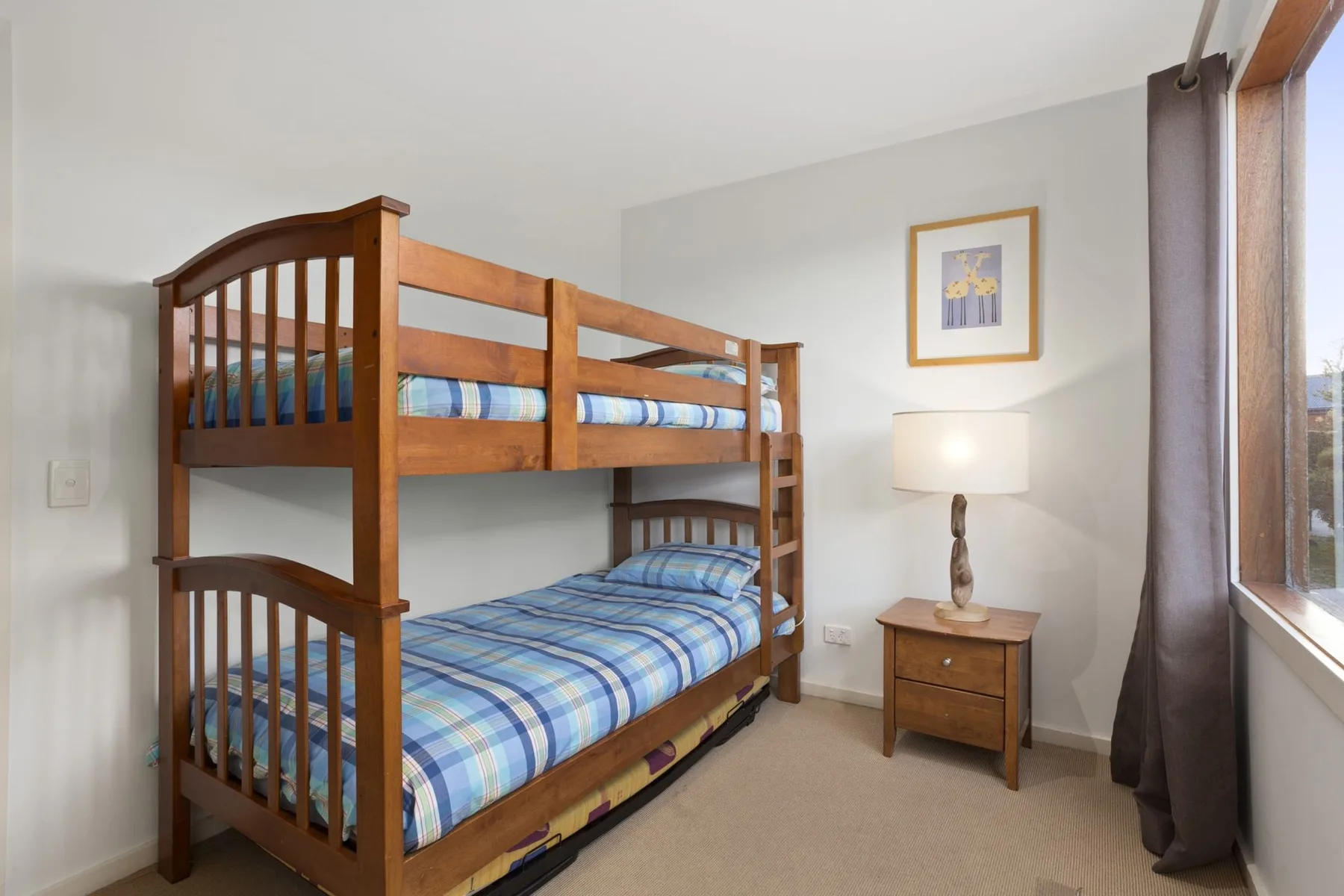 Un dormitorio con una litera de madera y una lámpara de noche.
