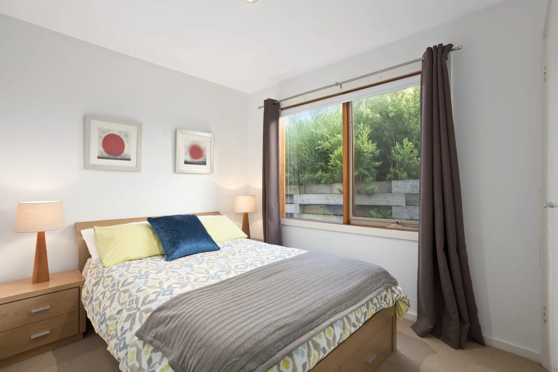 Dormitorio con una cama doble y una ventana grande con vistas a la vegetación.