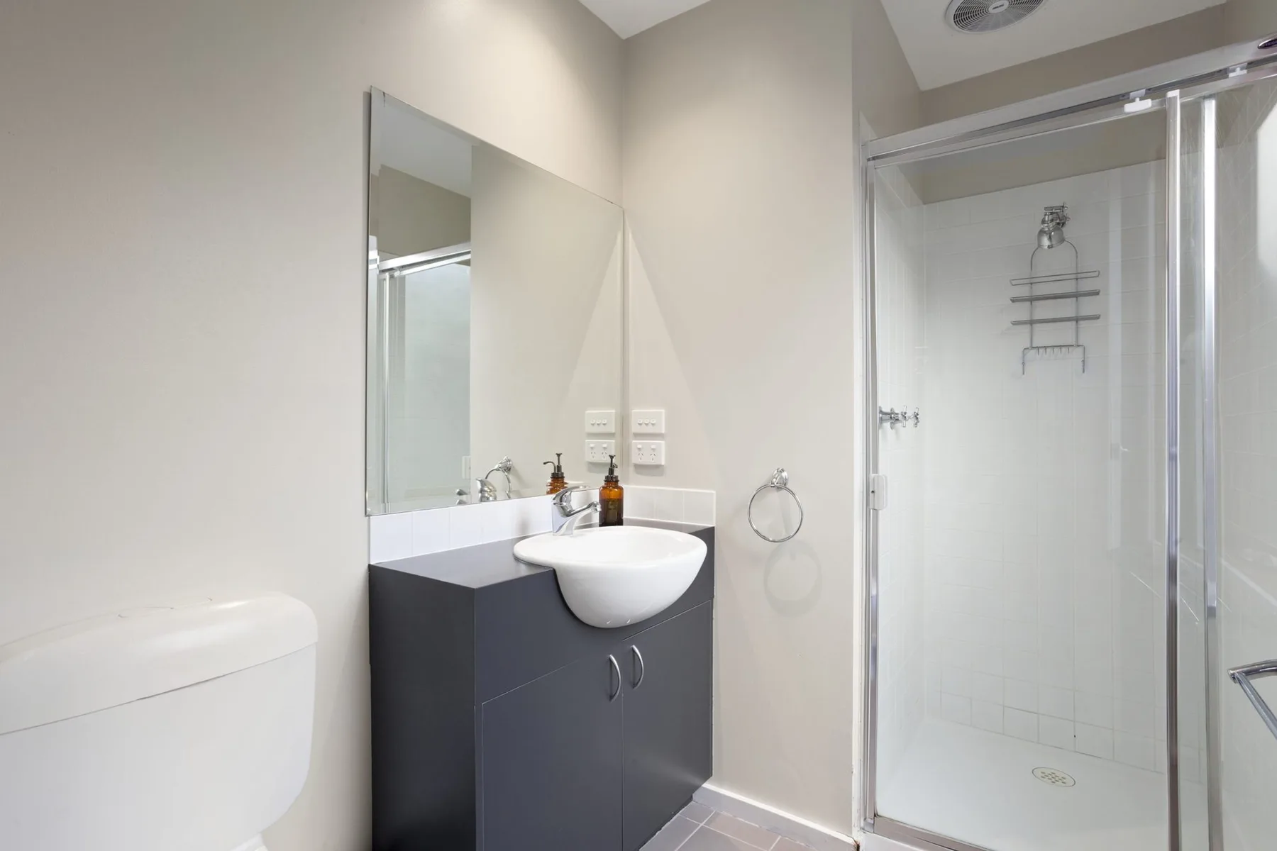 Un baño moderno con lavabo, mueble de baño y ducha de cristal.
