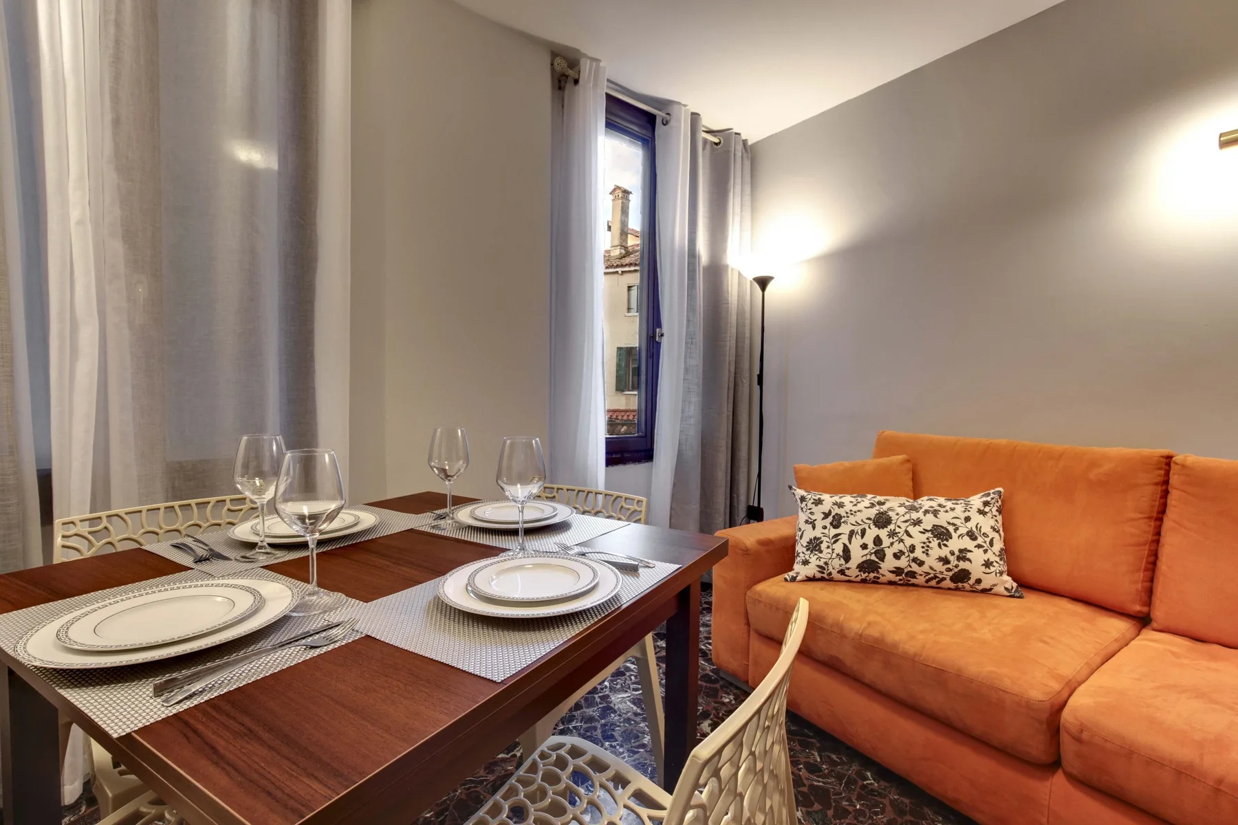 Comedor con una mesa puesta junto a un sofá naranja.