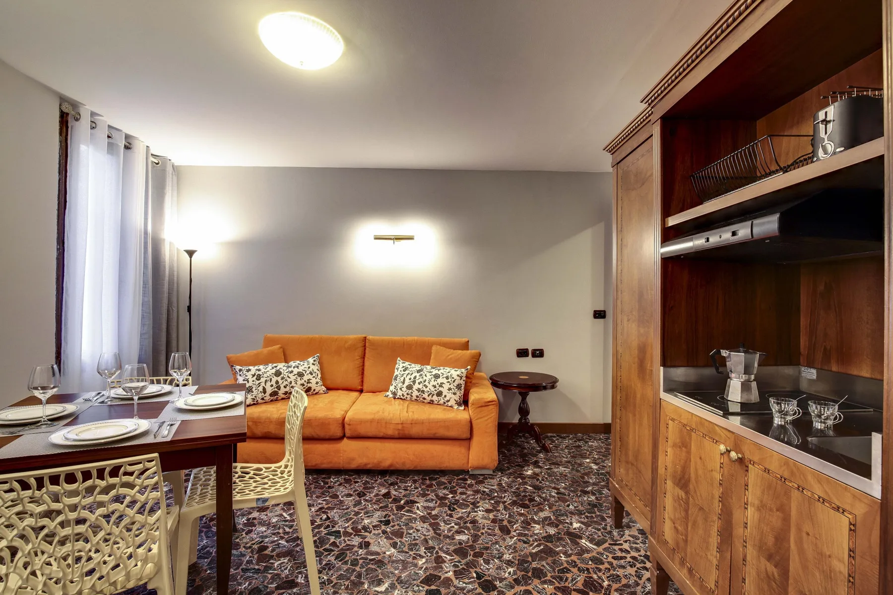 Una sala de estar y comedor con un sofá naranja y una mesa puesta.