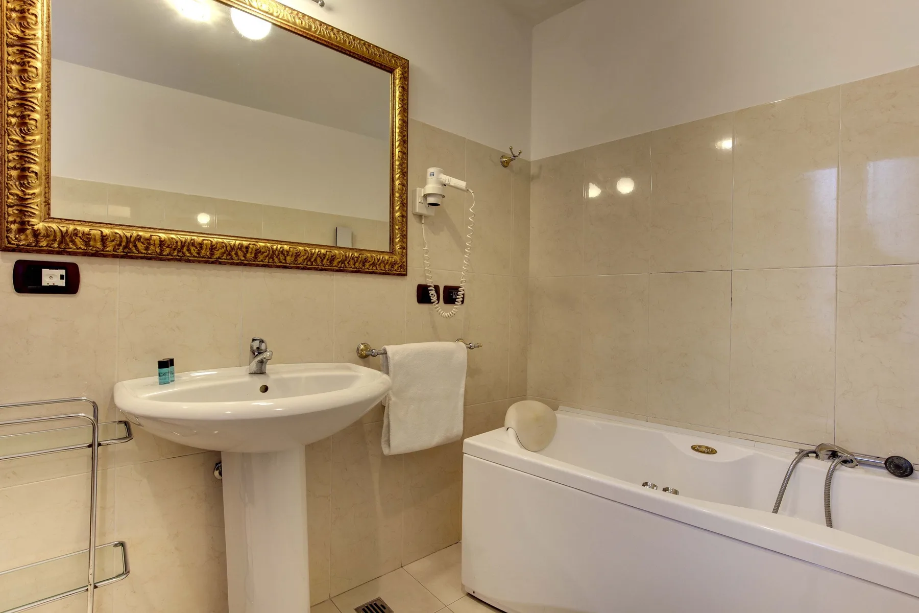 Un baño con bañera, lavabo y un gran espejo de pared.