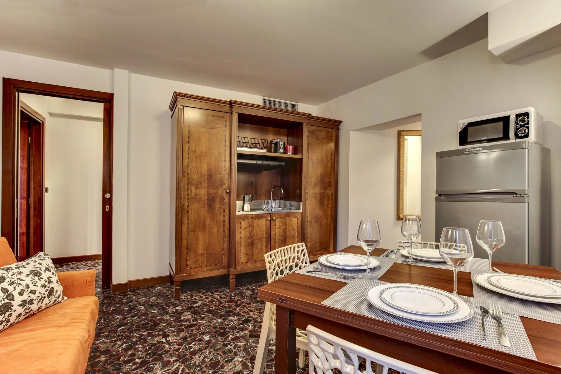 Un comedor con una mesa de madera puesta con platos y copas.