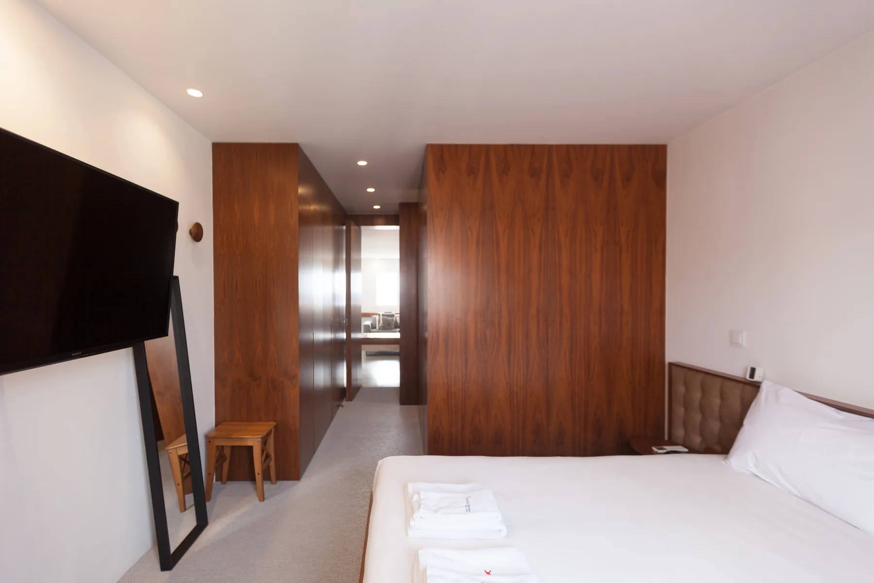 Un dormitorio con cama, armarios revestidos de madera y un televisor en la pared.