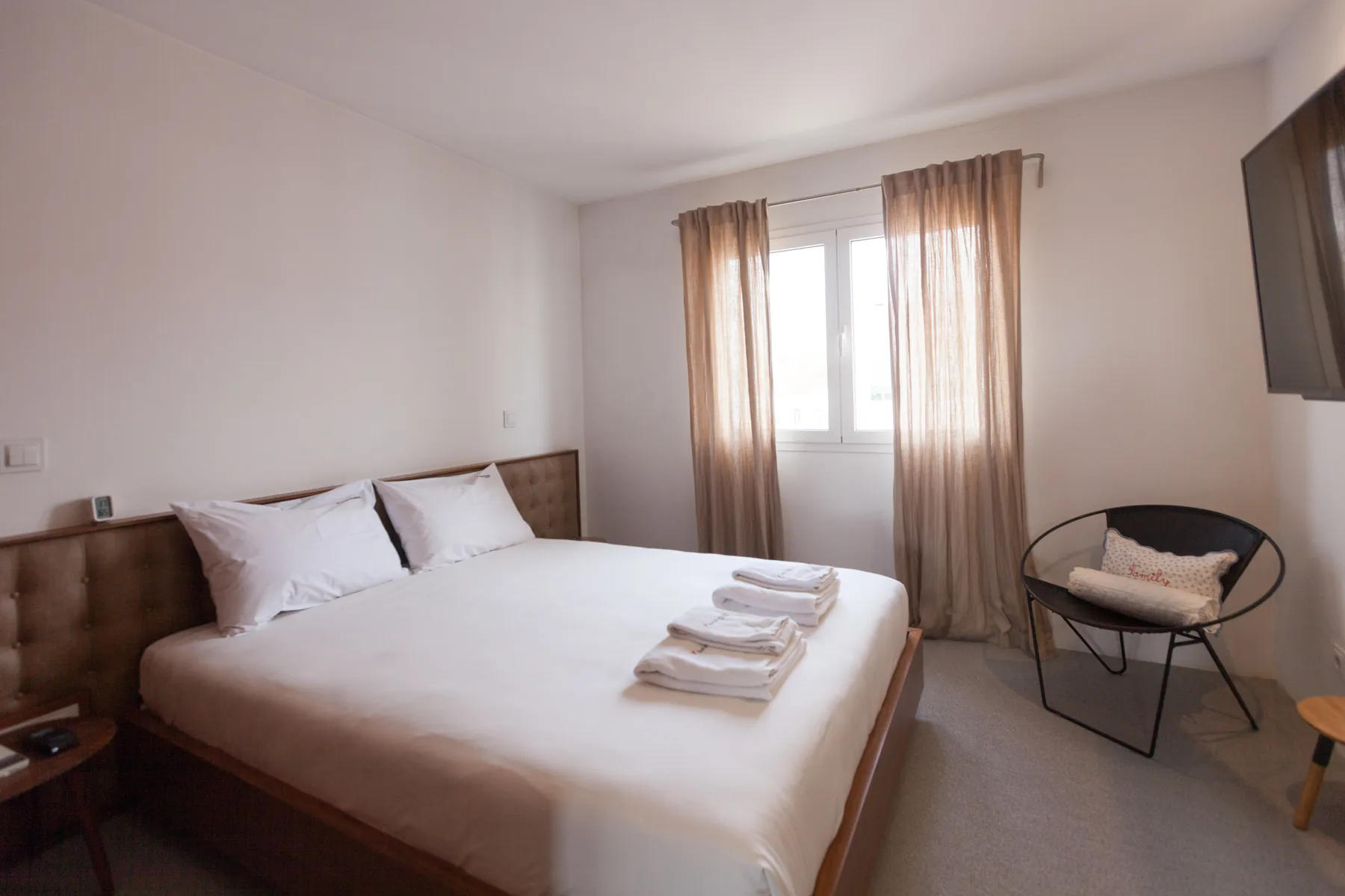 Dormitorio con una cama bien arreglada, una ventana y una silla.