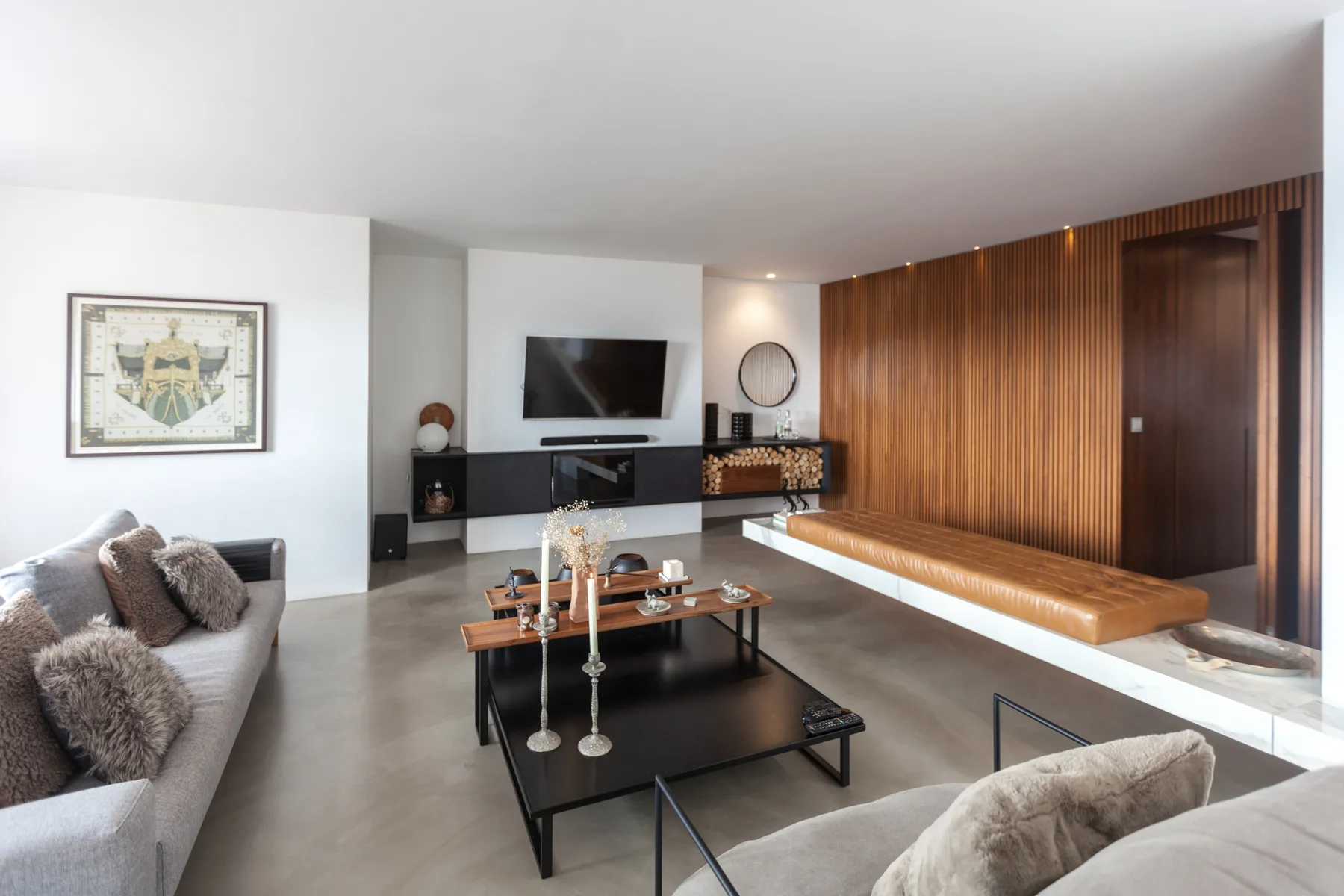Un salón moderno con asientos, una mesa baja y un televisor montado en la pared.