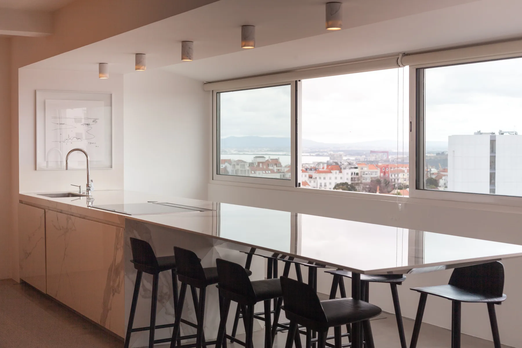 Una cocina moderna y una barra de comedor dan a una vista urbana por grandes ventanales.