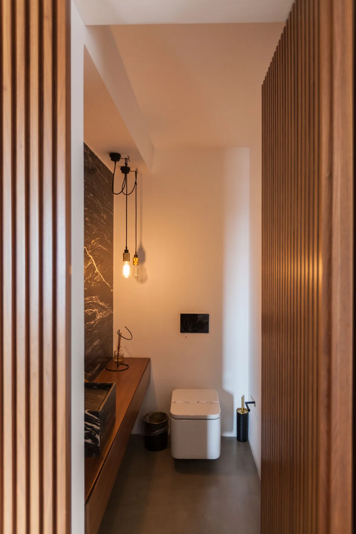 Un baño moderno con inodoro, tocador y luces colgantes.