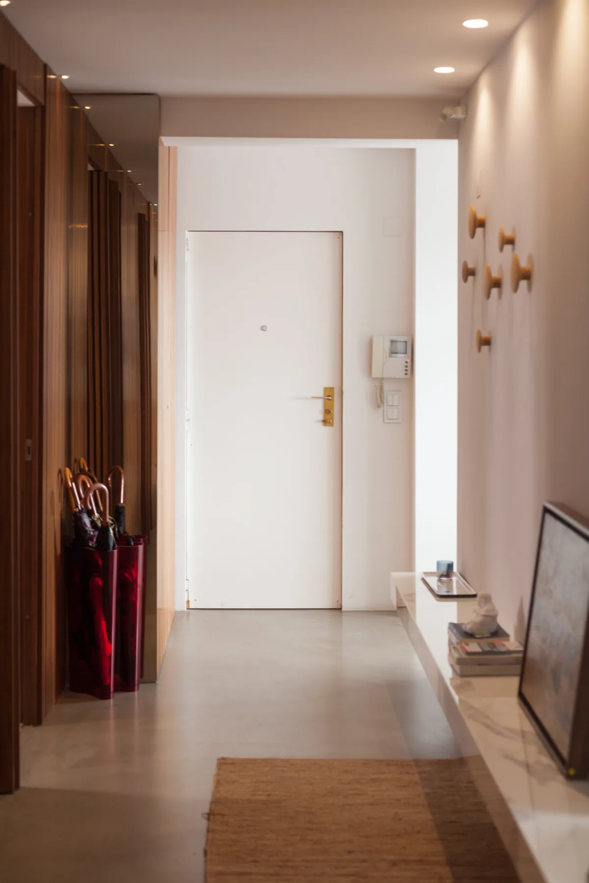 Un recibidor de apartamento con una puerta blanca y muebles de madera.