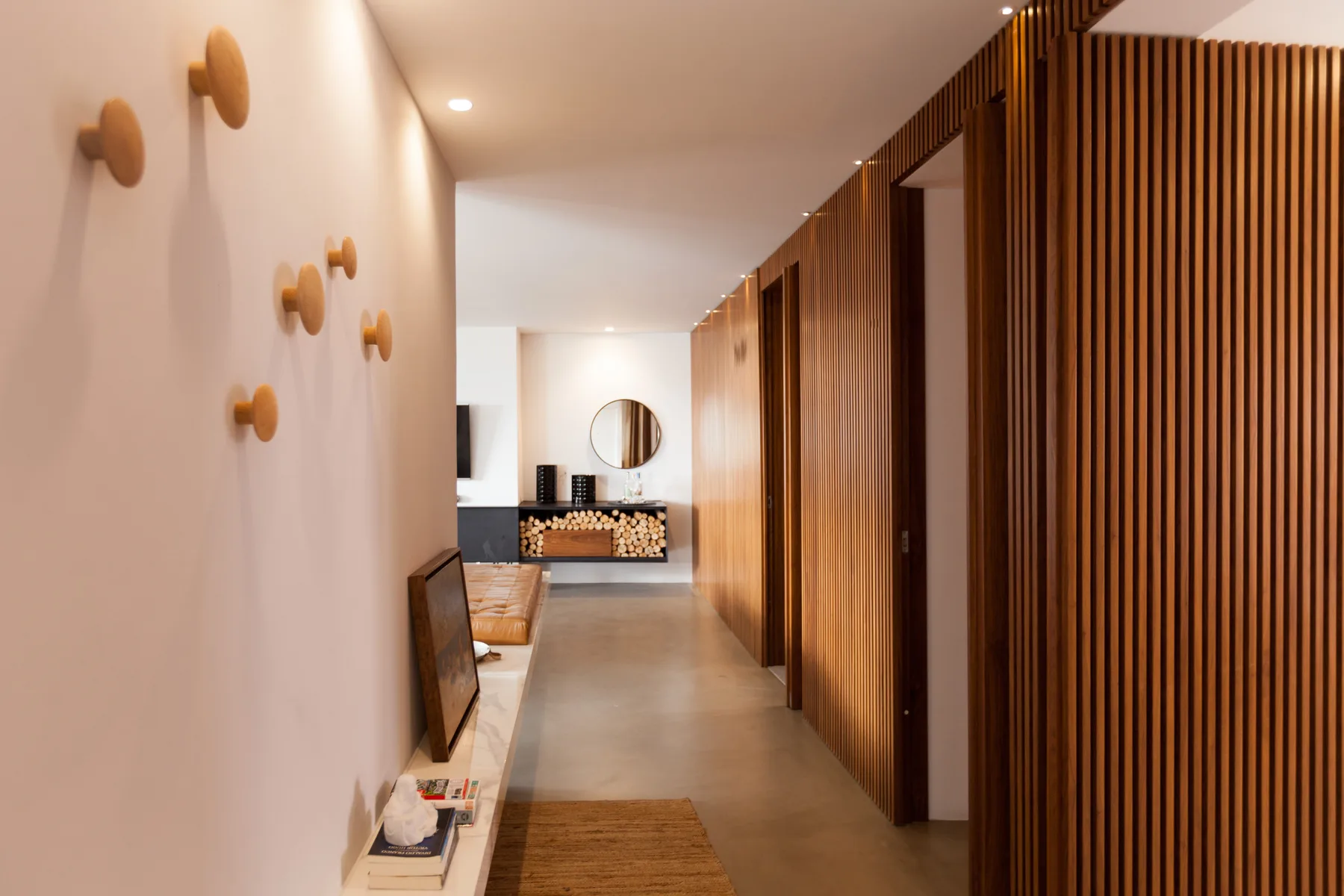 Un pasillo moderno con una celosía de listones de madera y una consola al fondo.