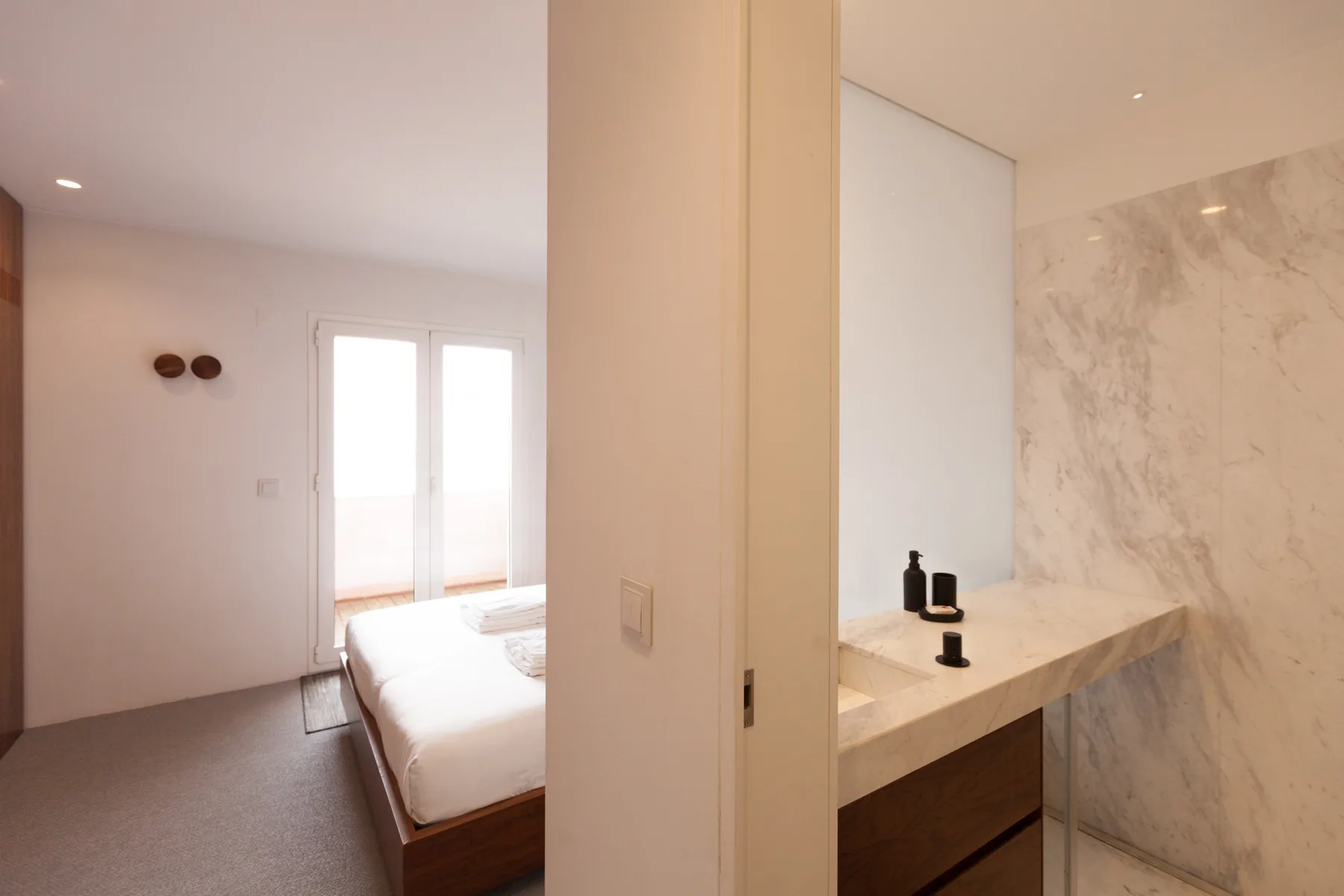 Un dormitorio y un baño contiguo con una cama y un lavabo de piedra.