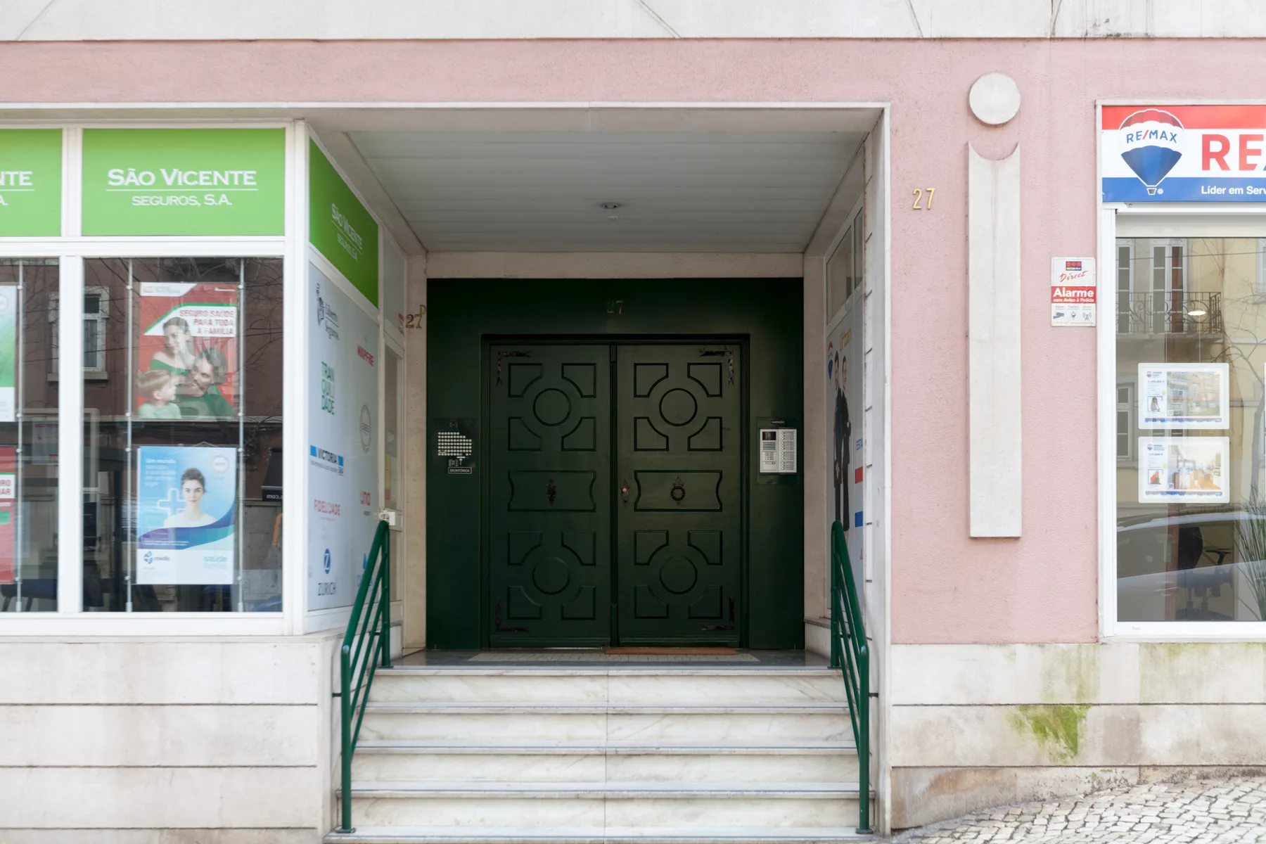 Una entrada retranqueada con escalones conduce a unas puertas dobles de color verde oscuro.