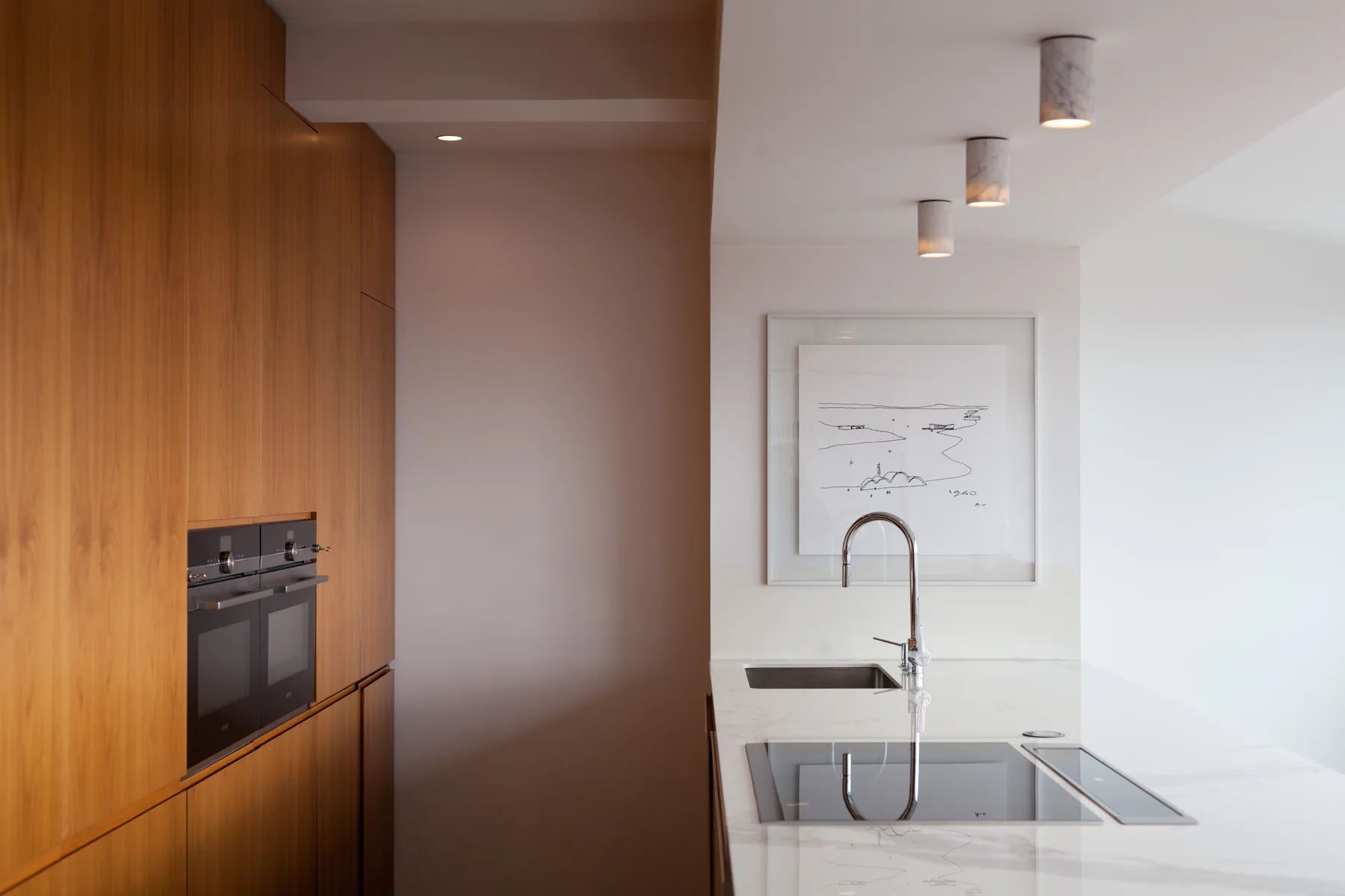 Una cocina moderna con armarios de madera, una placa de cocina y un fregadero.