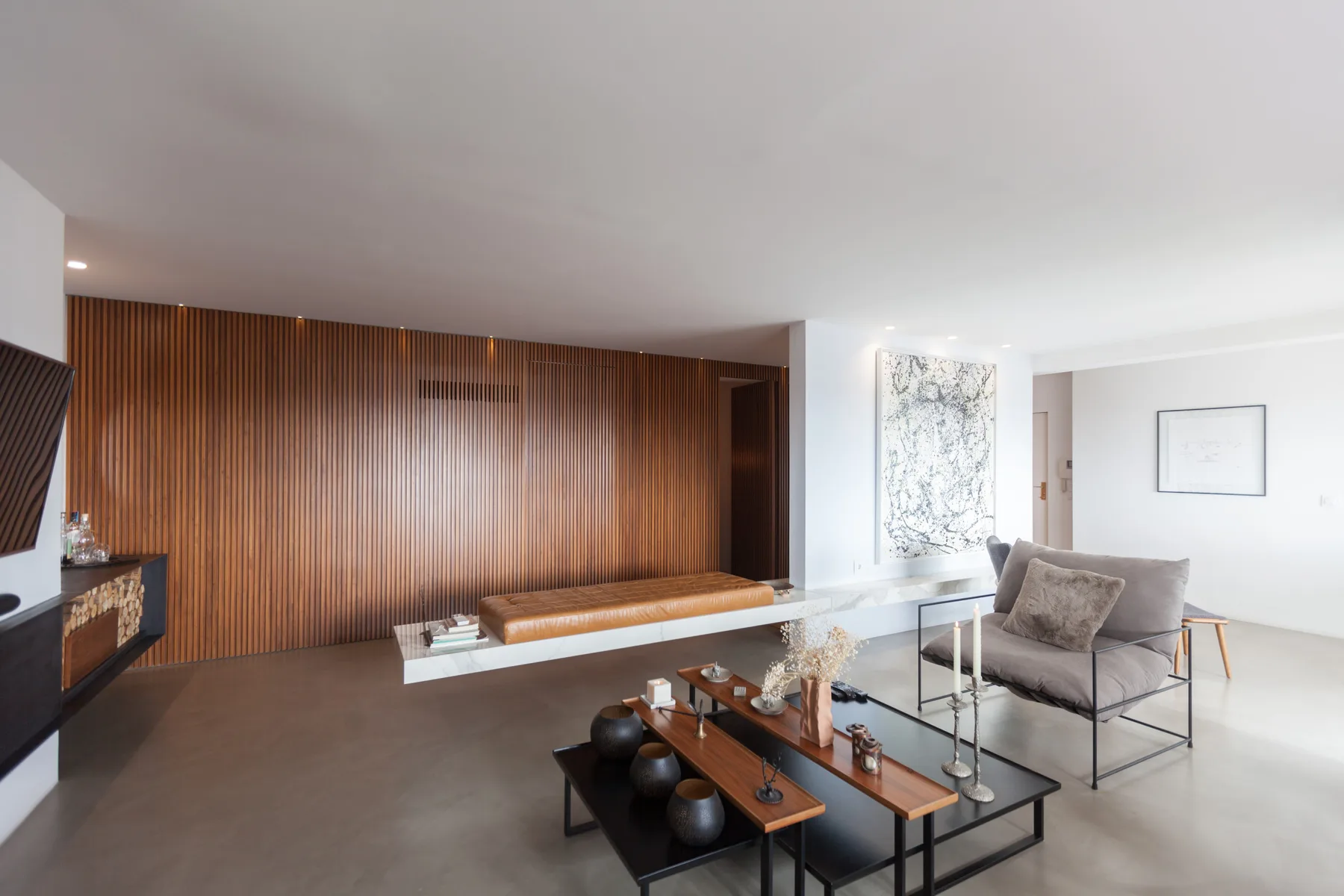 Una sala de estar moderna con una pared revestida de madera y asientos alrededor de una mesa de centro.