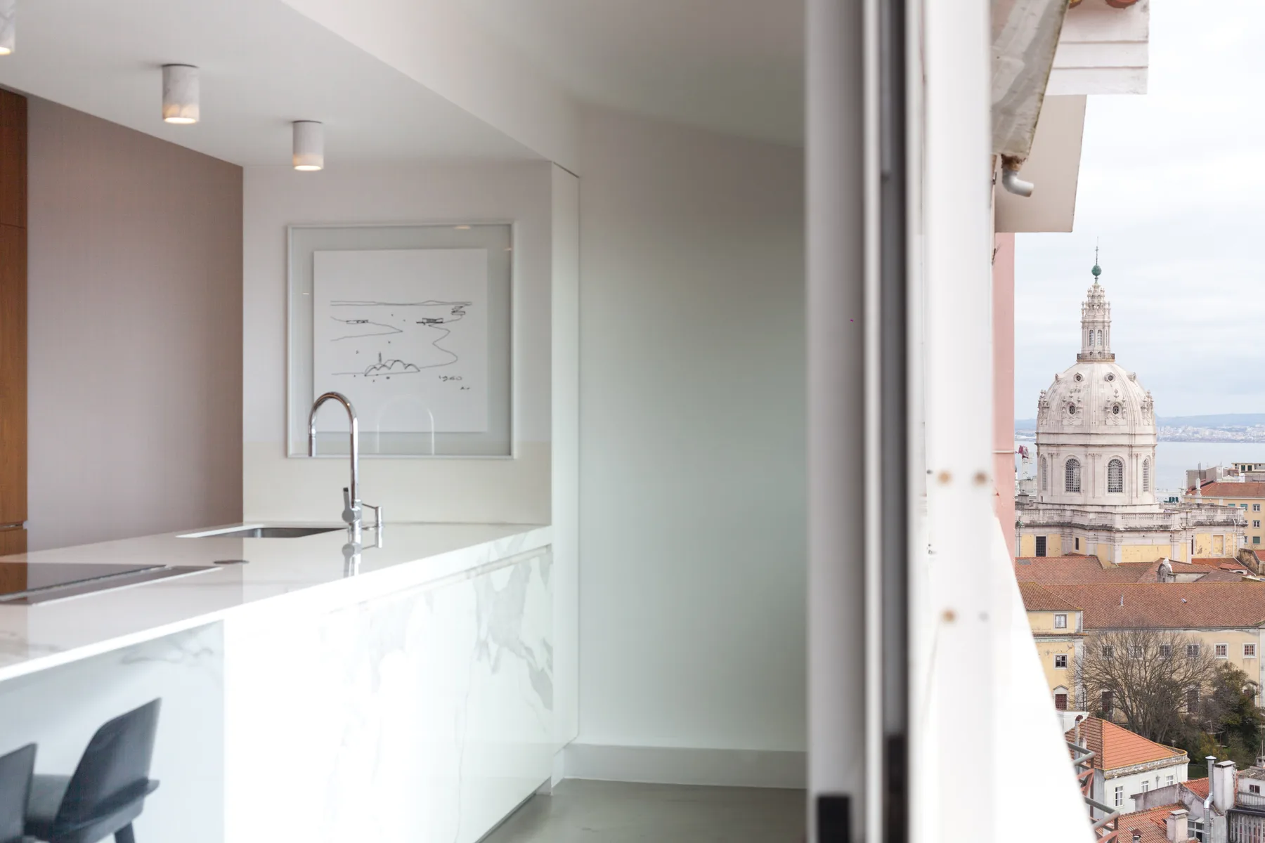 Una cocina moderna se abre a una vista urbana, con una torre abovedada visible afuera.