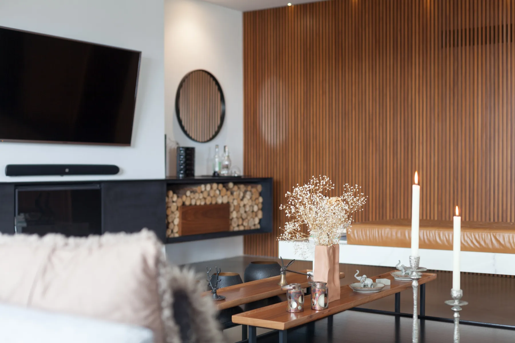 Sala de estar con televisor, pared de listones de madera y mesa de centro.