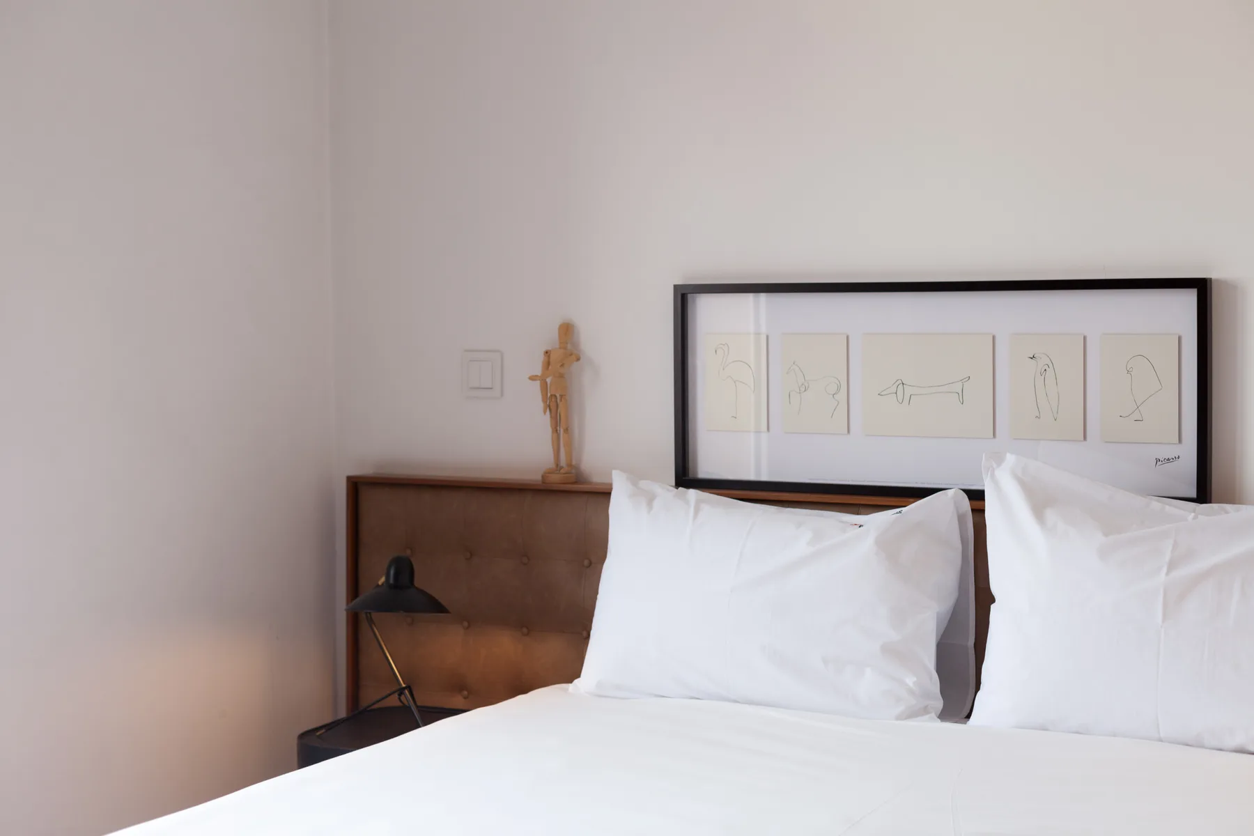 Dormitorio con una cama bien tendida y cuadros enmarcados sobre el cabecero.