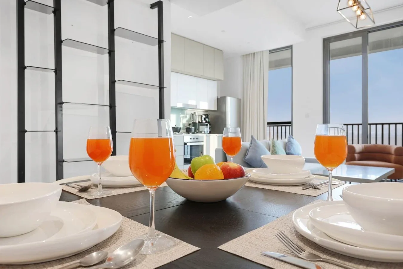 Una mesa está puesta con platos y copas en un comedor moderno y luminoso.