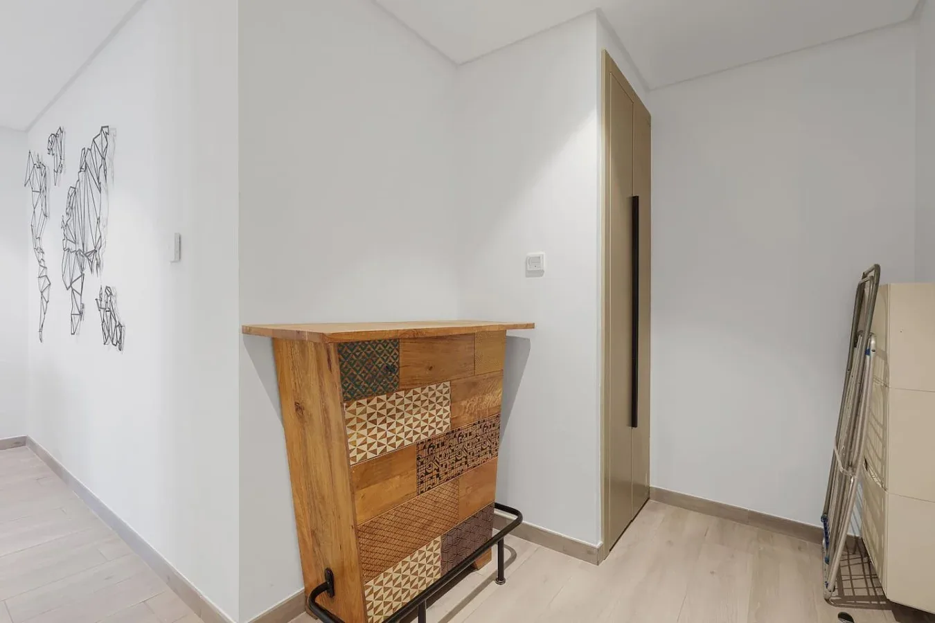 Un pasillo luminoso con un mueble de madera estampado y arte minimalista en la pared.