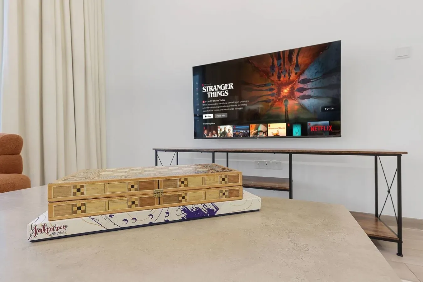 Una sala de estar con un televisor que muestra un menú de streaming sobre una consola baja.
