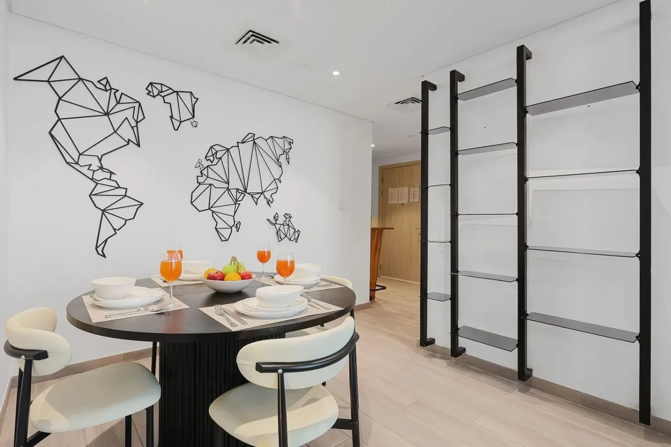 Un comedor con una mesa redonda preparada bajo un mapamundi geométrico en la pared.