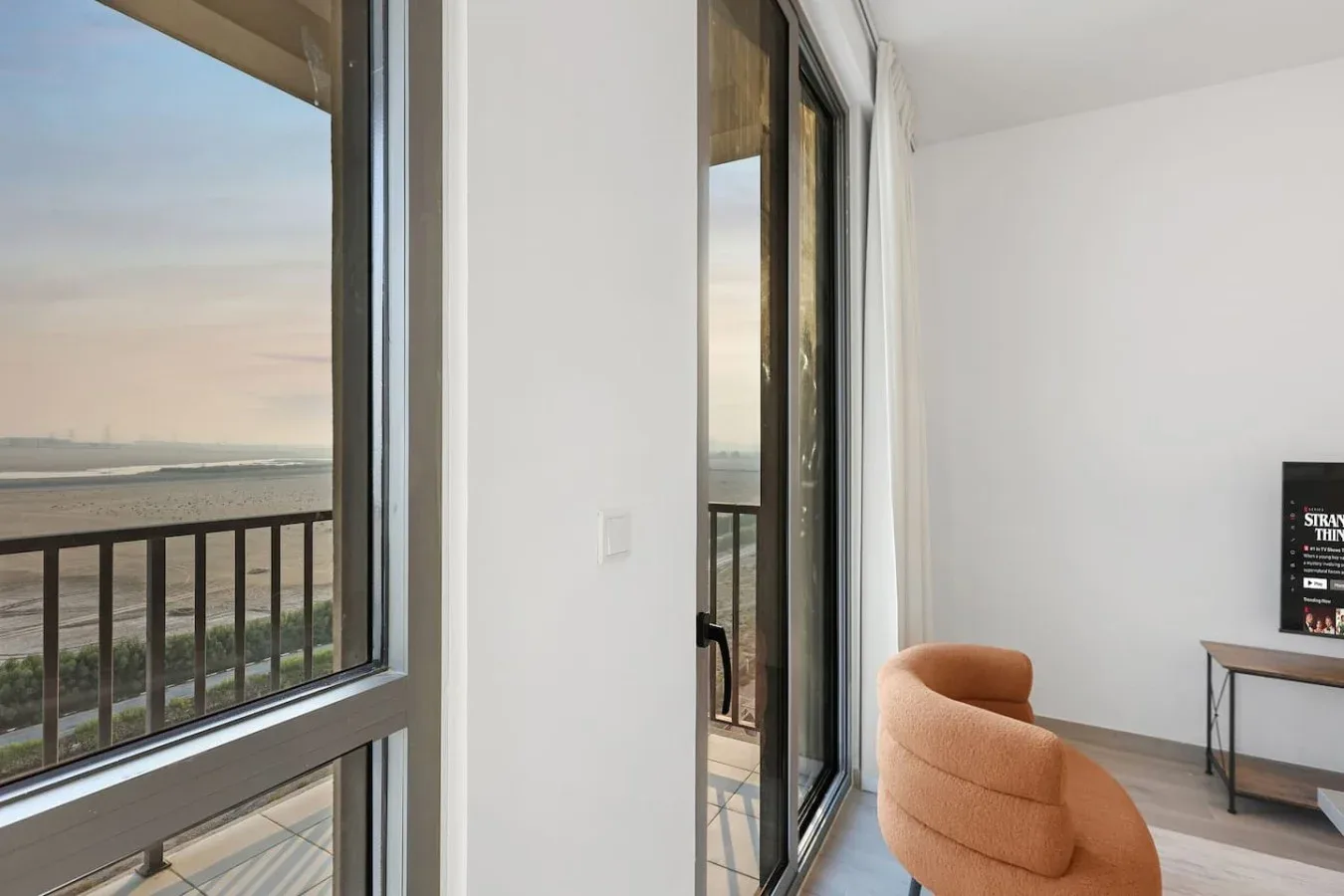Una habitación luminosa con ventanales de piso a techo frente al agua.