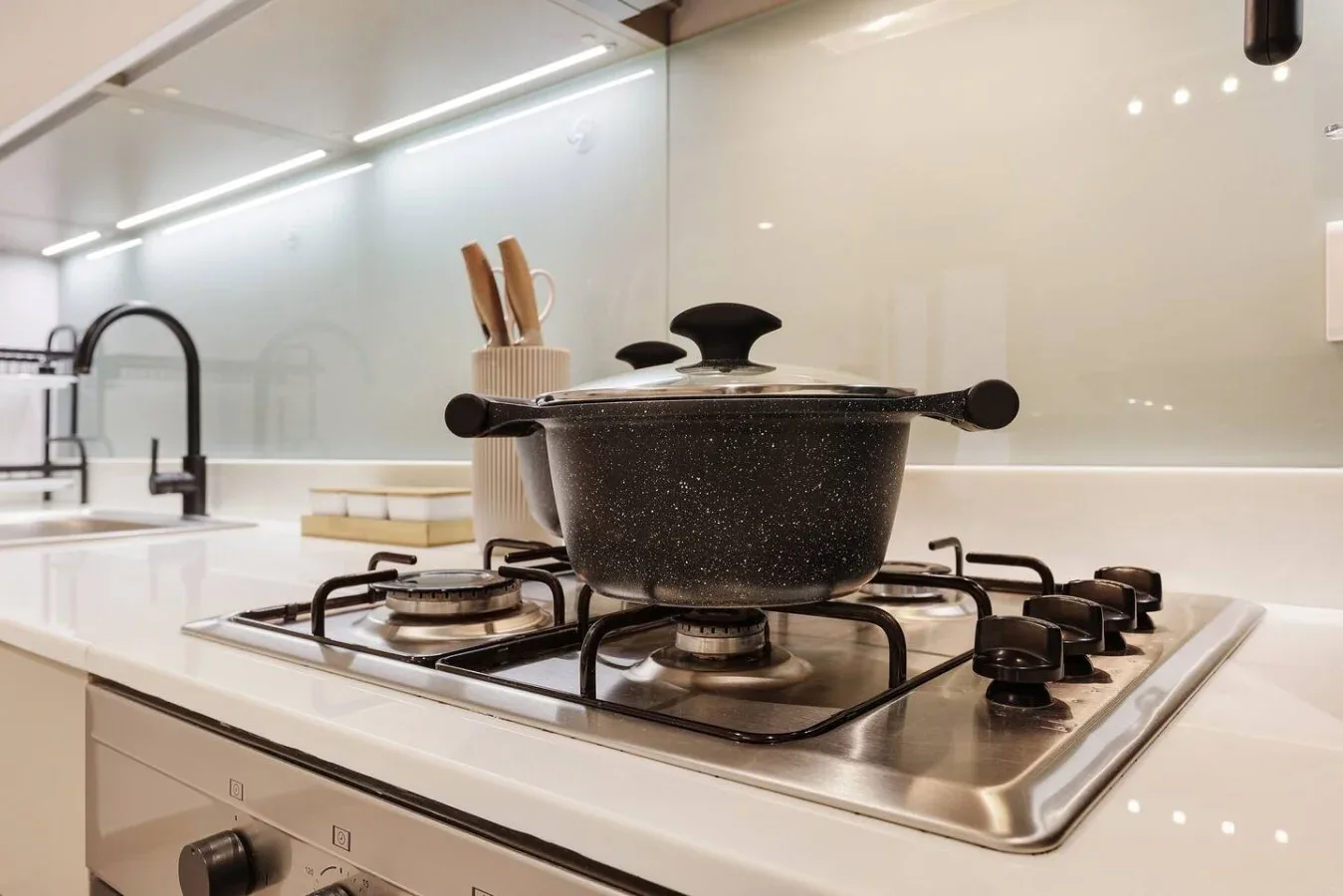 Una cocina moderna con una olla tapada sobre una estufa de gas.