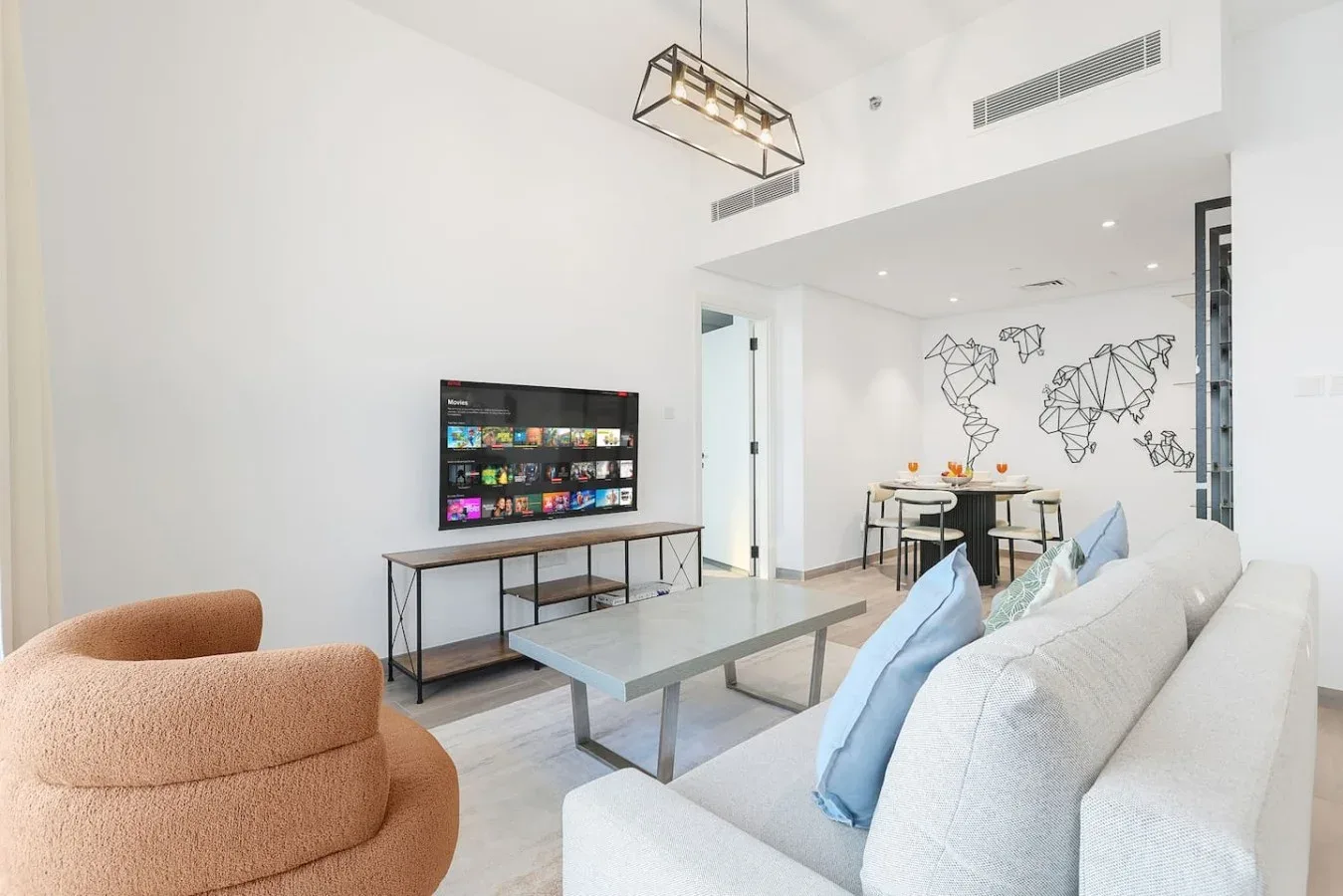 Una sala luminosa con televisor, asientos y un comedor.