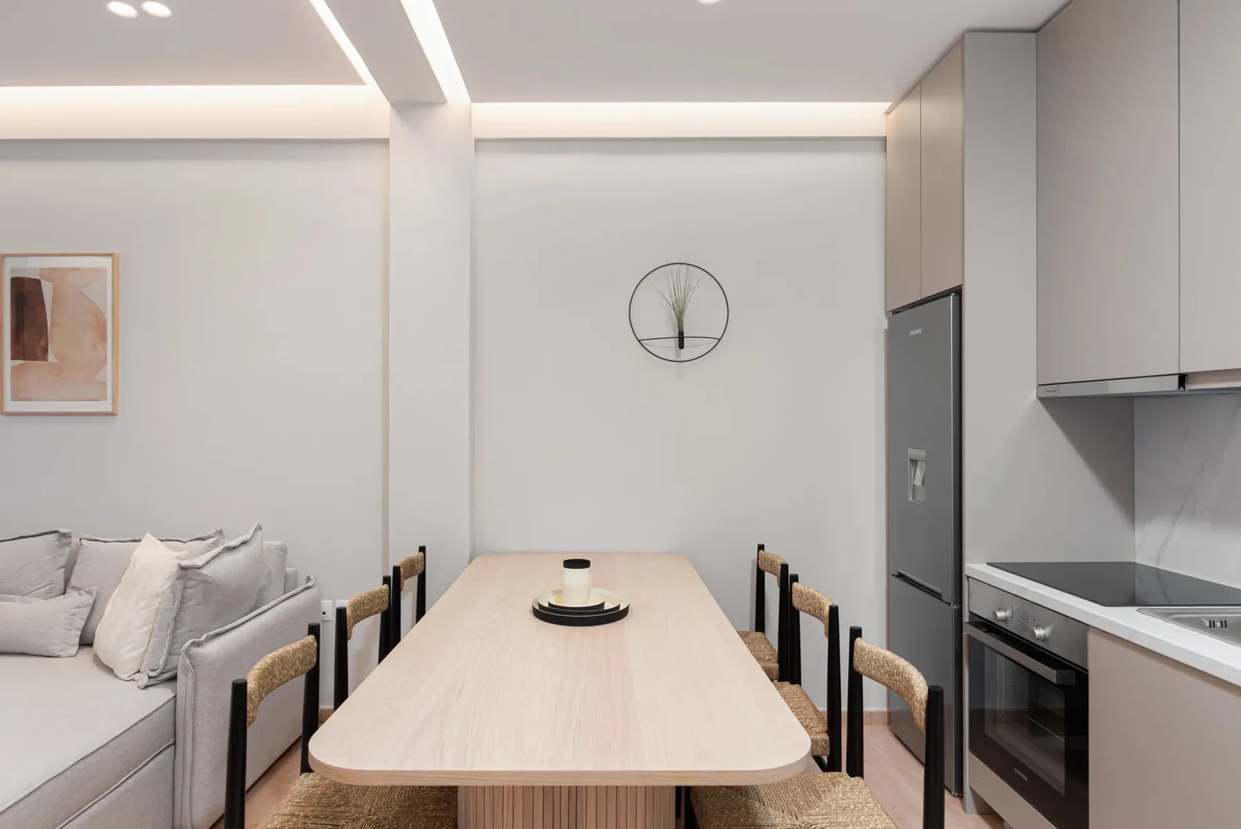 A dining area with a long table and seating beside a kitchen.