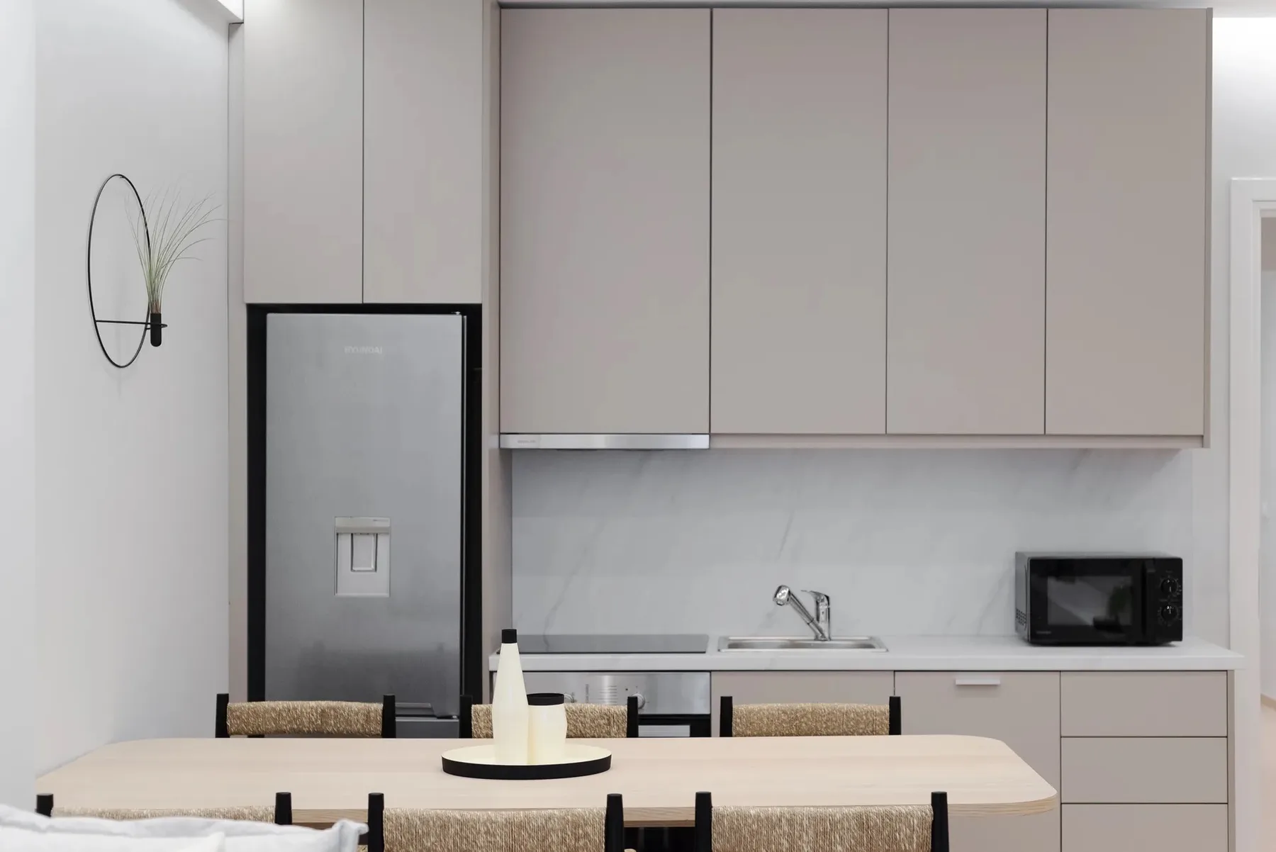 Una cocina moderna y comedor con armarios claros y una mesa.