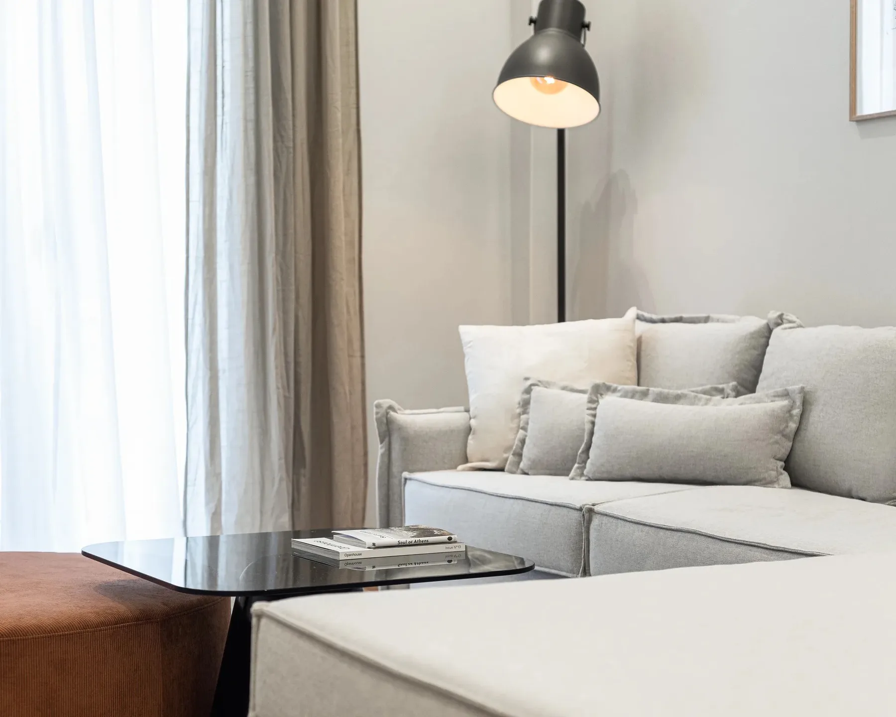 Una sala de estar con asientos claros y una lámpara de pie negra.