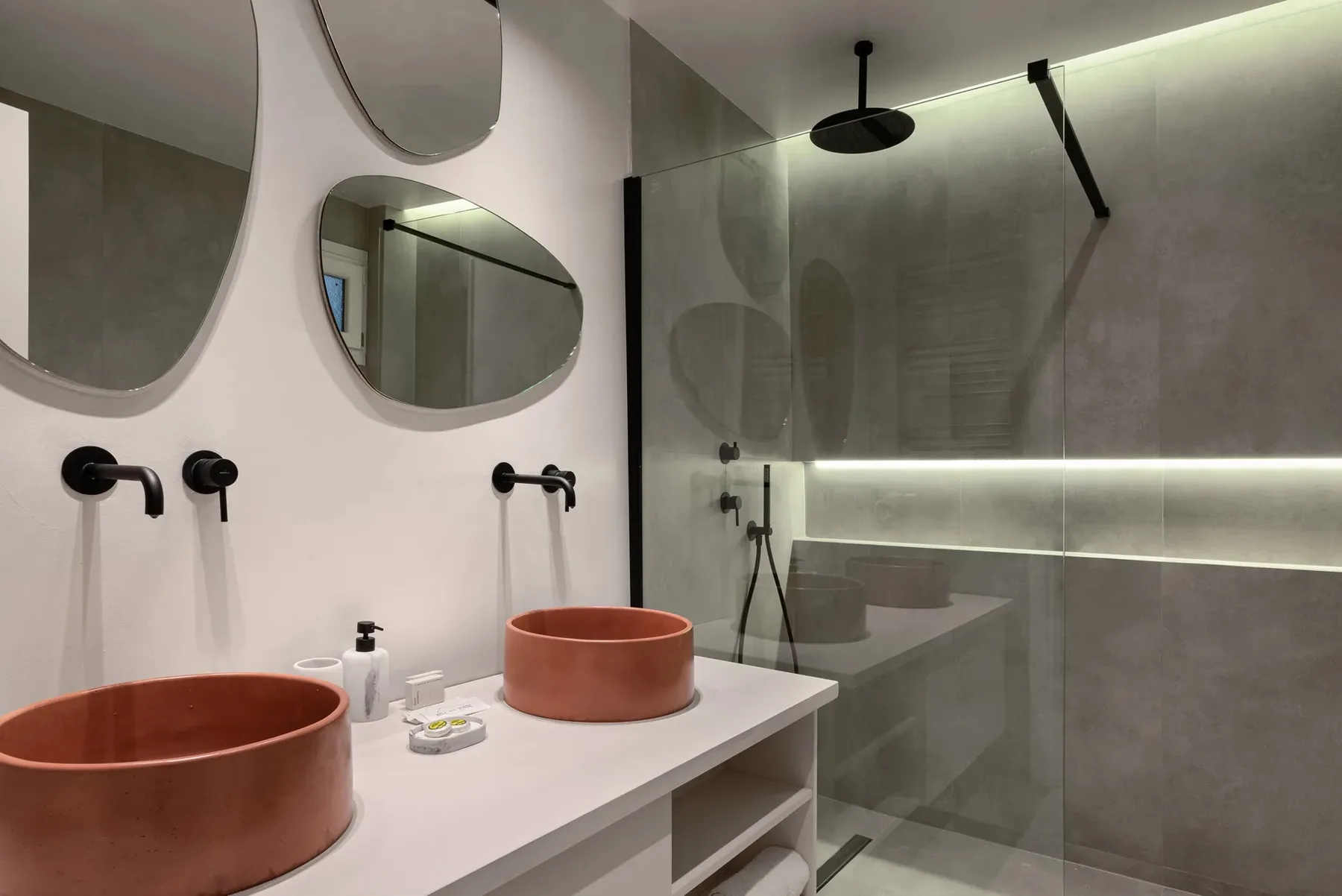 A modern bathroom with two round vessel sinks and a glass shower.