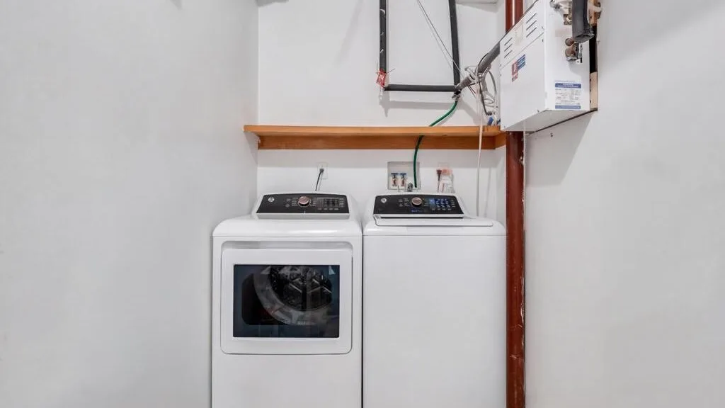 Una zona de lavandería con una máquina de carga frontal junto a una de carga superior.