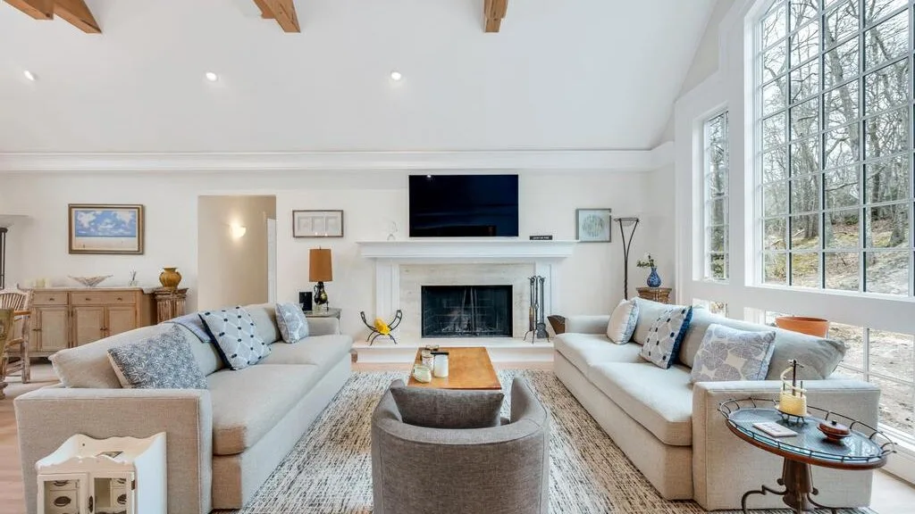 A bright living room with seating arranged around a fireplace and television.