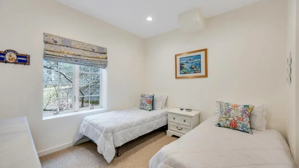 Un dormitorio luminoso con dos camas individuales junto a una ventana.